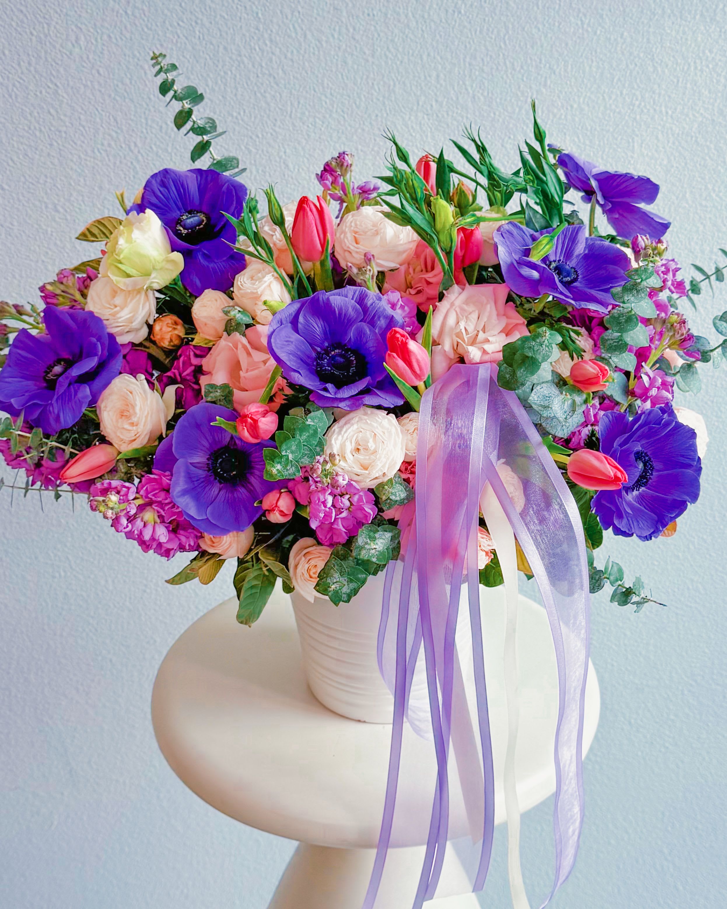 Bloom Boom - Check out this bouquet—it’s straight-up gorgeous! A total mix of soft, dreamy roses, bold pops of anemones, and cute lil’ tulips giving that fresh, playful vibe. The purples, pinks, and creams make it classy but with just the right touch of fun. That sheer ribbon? Yeah, that’s the cherry on top. Whether you’re flexin’ on a date, surprising your bestie, or just treatin’ yourself—this one’s a winner!