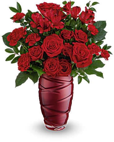  Love Blossoms Bouquet - Express your feelings boldly with this striking Valentine's Day bouquet of stunning red roses, elegantly arranged in a pearlescent glass vase featuring a captivating swirling design. This Valentine's Day arrangement features vibrant red roses, red spray roses, and rich red alstroemeria, along with charming red carnations. Accented with lemon leaf and huckleberry, this bouquet is beautifully presented in a Loving Swirls vase.