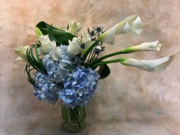 Flow With the Go Flow With the Go - Asymmetrical arrangement with callas and Asiatic lilies, blue hydrangea, roses, aspidistra leaves and lily grass.