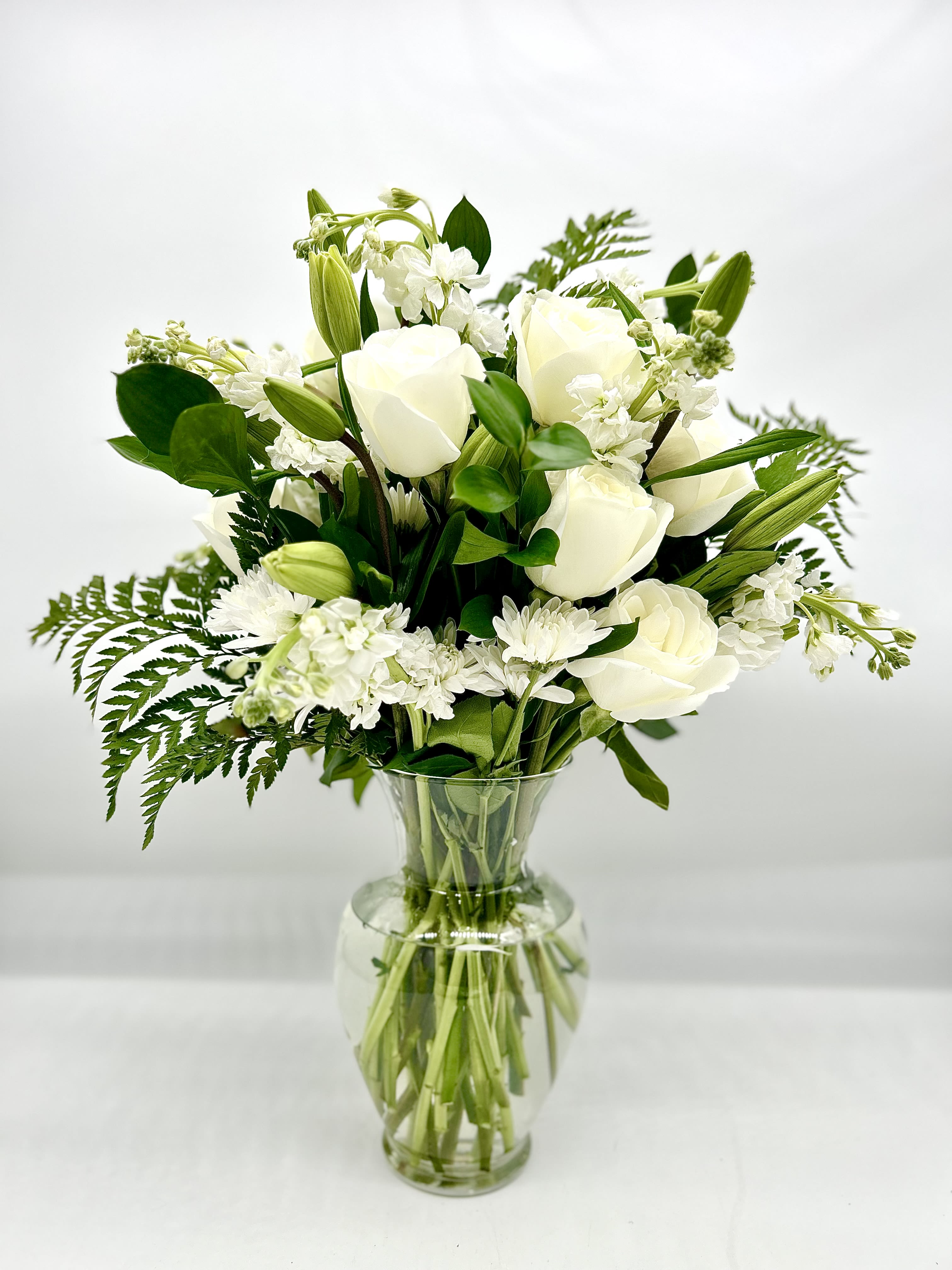 Everlasting Elegance  - This exquisite all-white floral arrangement captures the essence of timeless beauty and grace. Soft greenery subtly enhances the elegant white blooms, creating a sophisticated and serene aesthetic. Perfect for weddings, formal events, or as a statement piece in any home, &quot;Everlasting Elegance&quot; embodies purity, peace, and refined luxury. Its subtle fragrance and tranquil beauty make it a breathtaking addition to any space. All bouquets are arranged by our professional floral design team accented with seasonal filler (i.e. greenery, baby’s breath, etc.) inside an elegant glass vase or gift box. When artistically designed in a clear glass vase arrangement measures approximately 23&quot;H x 18&quot;L.   Blooms are hand delivered in person to enhance any celebration or a “just because” surprise. Deliveries are done between 10am - 5pm. If the recipient is not home we will leave the delivery if safe from the elements. We will call or text the recipient and let them know a delivery has been left. 