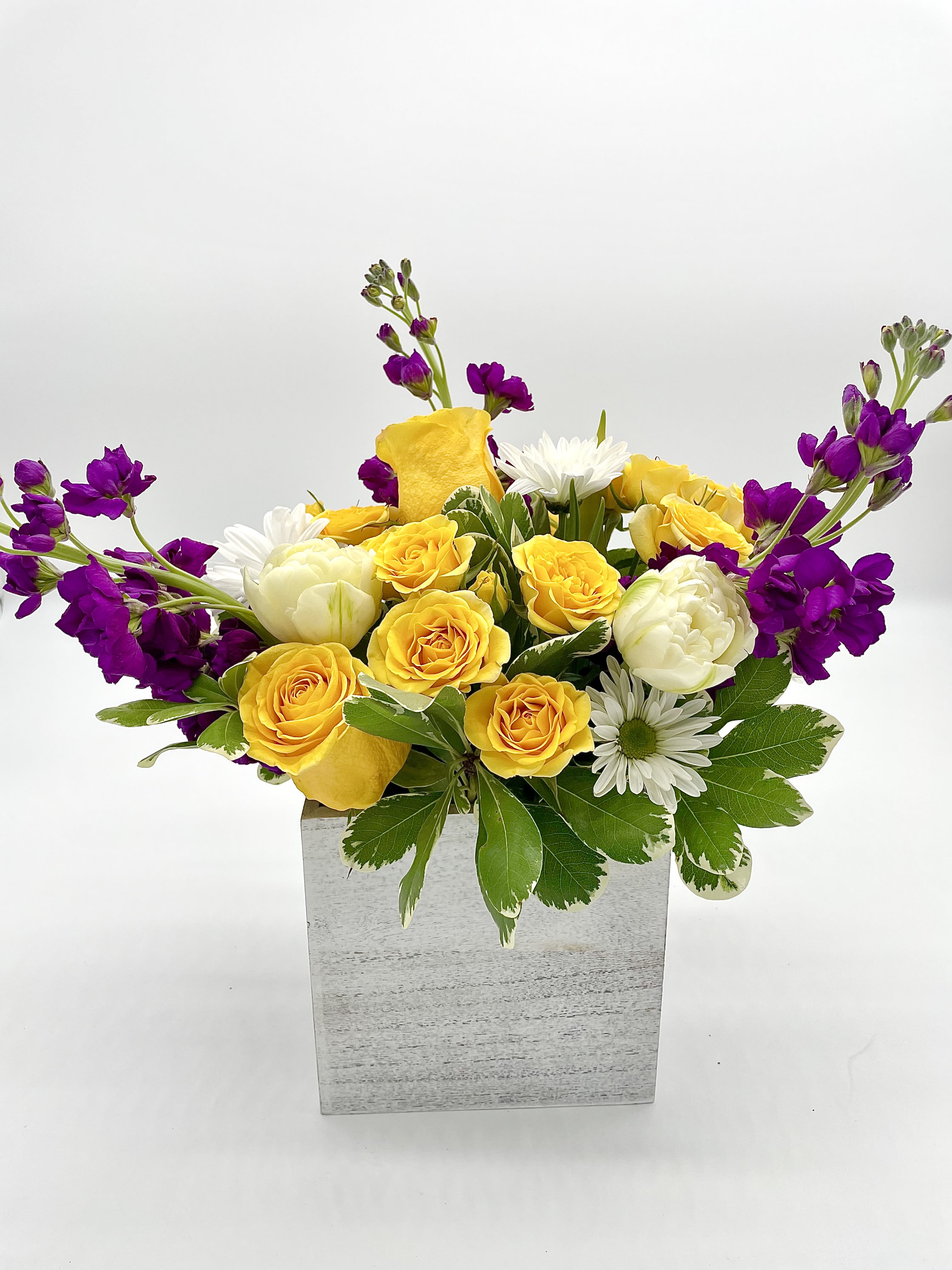 Sunshine & Serenity Sunshine & Serenity - This arrangement balances the bright, sunny yellow roses with the calm, serene feel of the white tulips and purple stock enhanced by the rustic charm of a white wooden vase. Blooms are hand delivered in person to enhance any celebration or a “just because” surprise. Deliveries are done between 10am - 5pm. If the recipient is not home, we will leave the delivery if safe from the elements. We will call or text the recipient and let them know a delivery has been left.