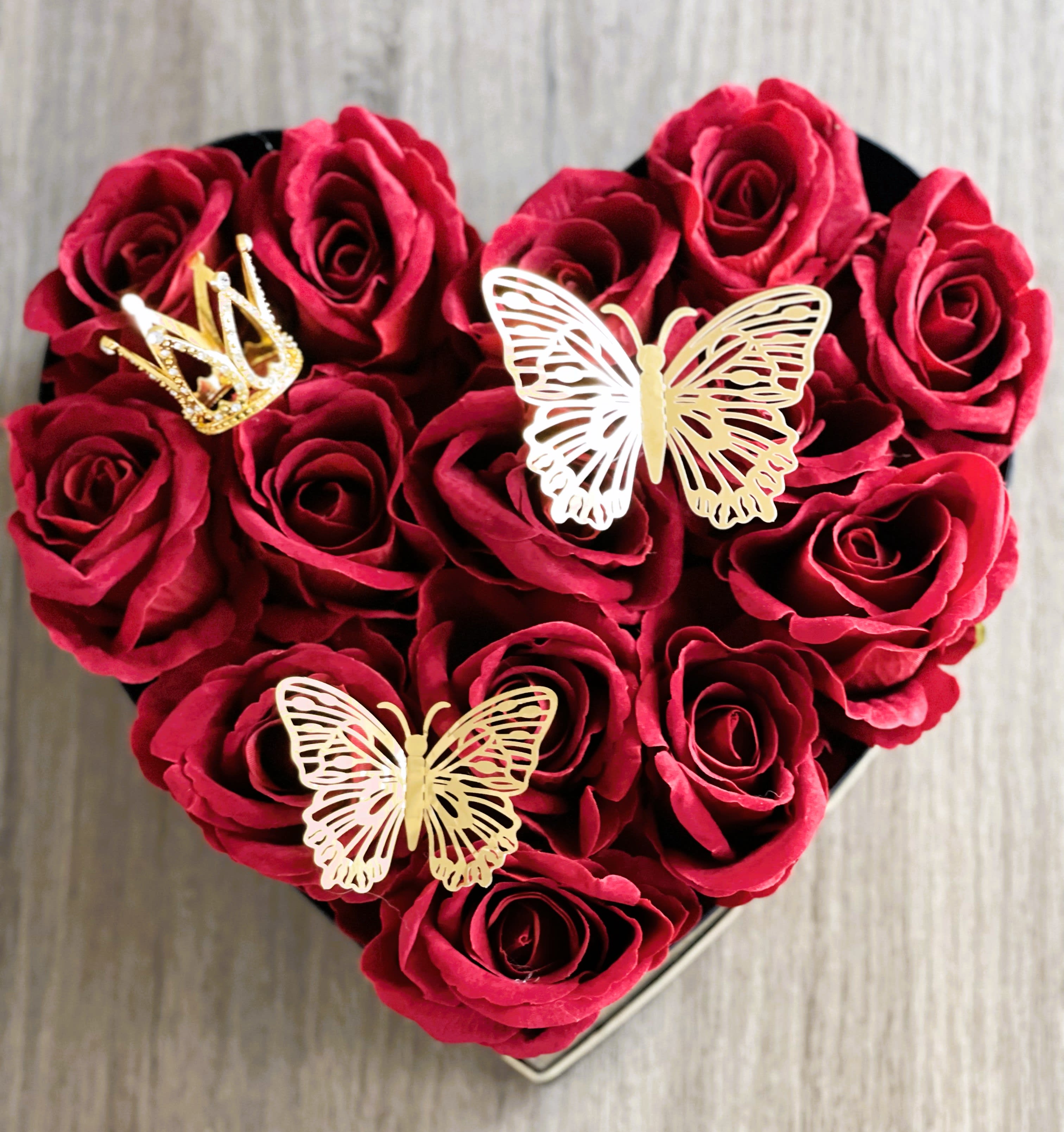 Heart Shape Black  Box With 16 Red Roses - Discover the delight of giving with our collection of stunning rose boxes. Available in three sizes – small (16 roses), medium (22 roses), or large (30 roses) – each box is beautifully decorated with your preferred fresh red roses. Personalize your box further by selecting from a variety of elegant box colors, including pink, red, or black. These enchanting gift boxes also come with charming 3D butterfly stickers and a small crown. Experience the joy of gifting with our exquisite selection.