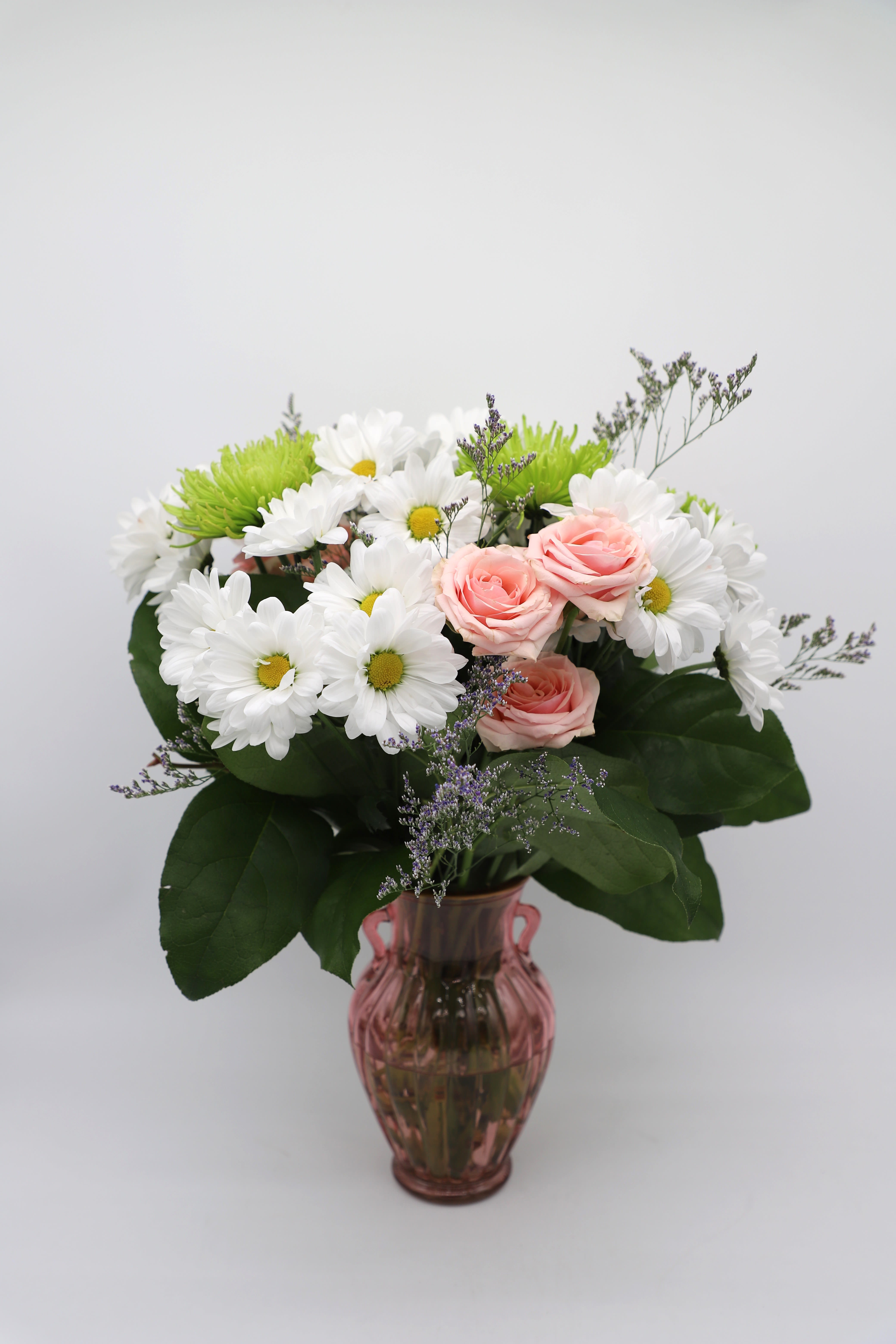 Pink Treasure - This flower arrangement comes with a stunning pink vase that is adorned with daisies, pink spray roses, and green spider mums.