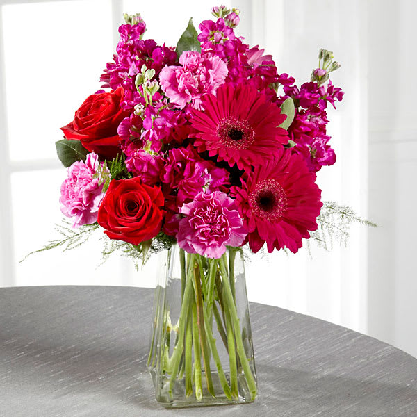 The FTD Pure Bliss Bouquet The FTD Pure Bliss Bouquet - The power of pink is packed into one beautifully blushing bouquet to make your recipient's day one they will never forget! Red roses make the hot pink petals of carnations gilly flower and gerbera daisies pop in this fun and fanciful flower arrangement accented with lush greens and presented in a gathered square clear glass vase. Berried bliss in every way this bouquet is set to create a standout birthday congratulations or thank you gift. GOOD bouquet includes 11 stems. Approx. 15"H x 9"W. BETTER bouquet includes 15 stems. Approx. 15"H x 10"W. BEST bouquet includes 19 stems. Approx. 16"H x 14"W.