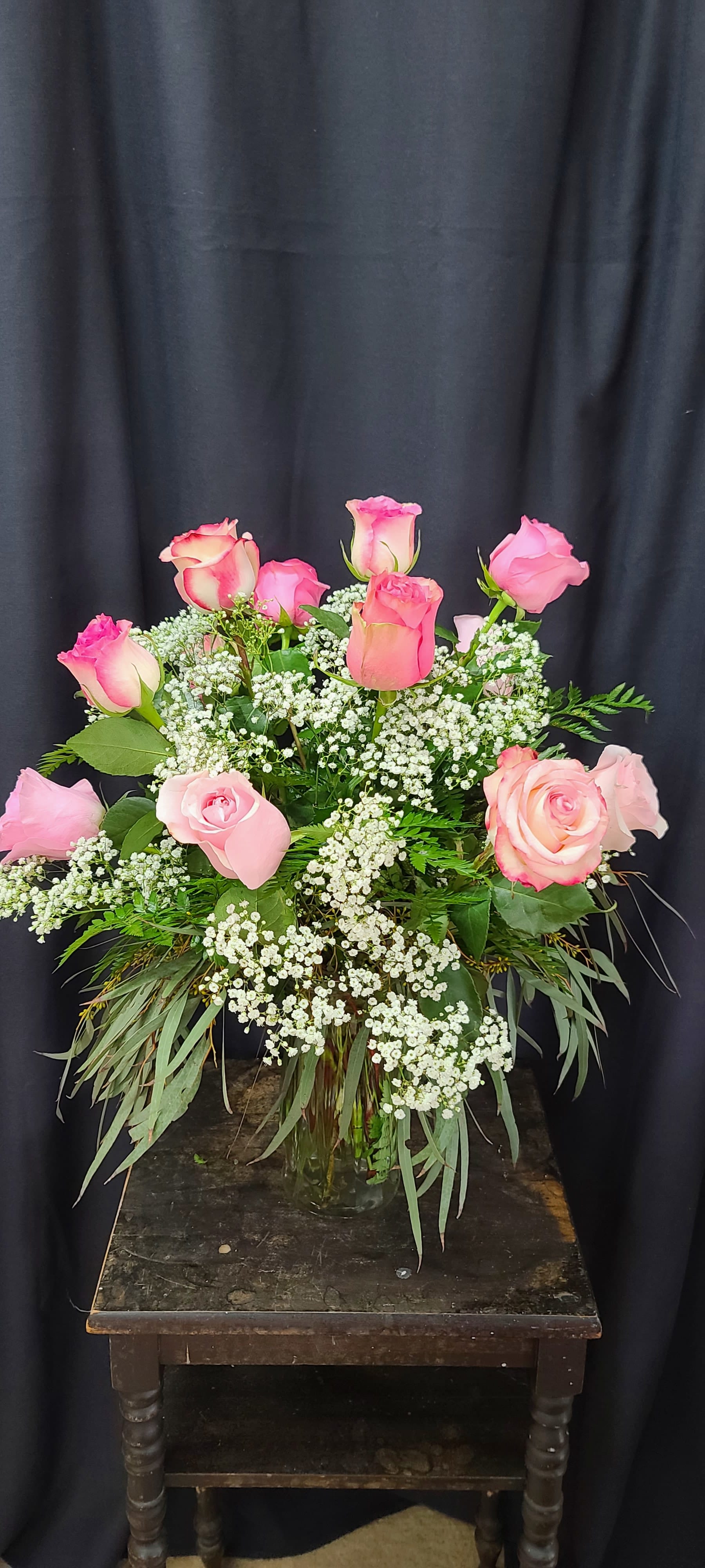 Pink Roses  - A gorgeous mix of 12 pink roses, soft, beautiful babies breath, draping eucalyptus  and fern arranged in a clear glass vase. Deluxe and Premium Designs have more roses.