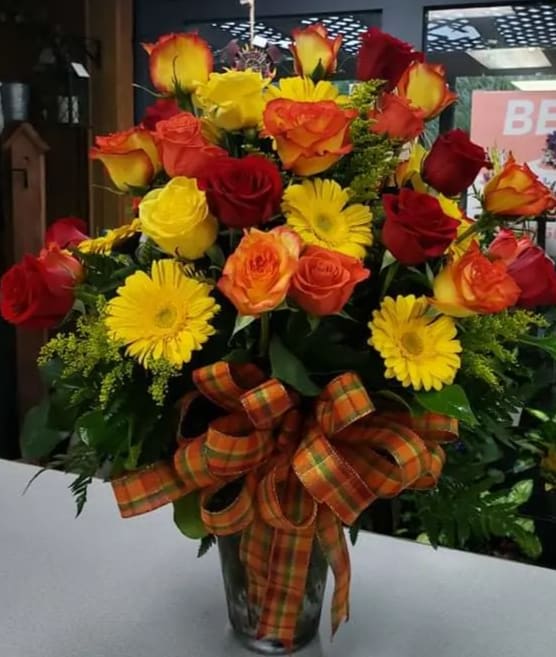 Sweet Sentiment  - Variety of colored roses, Gerbera Daisies, Solidago in a clear vase with a fall plaid ribbon.