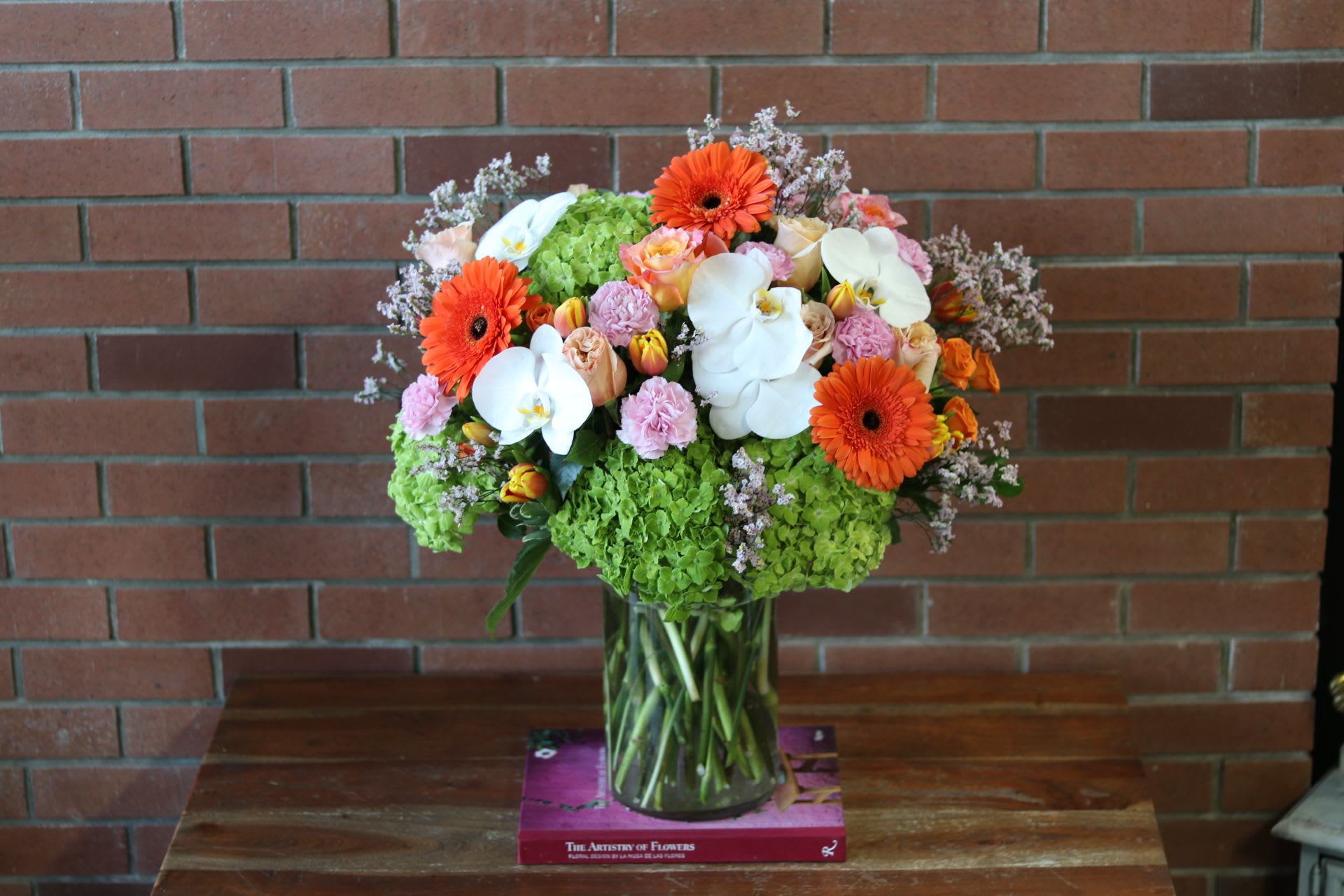 Vibrant Harmony  - &quot;Vibrant Harmony&quot; - This exquisite bouquet celebrates the beauty of nature's bounty, blending a vibrant palette of coral, pink, and green for a truly captivating presentation. Lush roses, cheerful gerbera daisies, and delicate tulips mingle with the lush fullness of green hydrangeas and the elegant grace of white orchids, creating a harmonious display that delights the senses. Perfect for brightening any space or expressing heartfelt sentiments, this stunning arrangement is a feast for the eyes and a symbol of life's joyful moments.