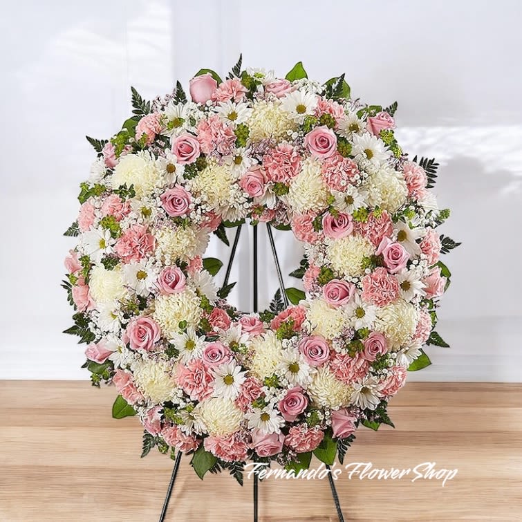 Blooming Legacy  - This graceful cremation floral arrangement is a dignified and heartfelt tribute. Designed to frame and honor an urn, it features a beautiful combination of white roses, chrysanthemums, and delphiniums, accented with soft blue flowers and eucalyptus greenery. The white flowers symbolize peace and purity, while the blue tones add a serene and calming touch. The arrangement’s thoughtful design exudes elegance and reverence, providing comfort and a sense of tranquility during a time of remembrance. A fitting way to celebrate a cherished life with love and dignity.  PICTURE SHOW PREMIUM