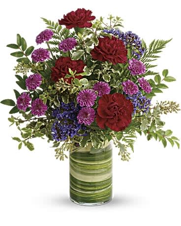 Teleflora's Vivid Love Bouquet - Rich and radiant, this vivid mix of jewel-toned blooms is wrapped with leaves for modern style, but its message of love is timeless. Maroon carnations, purple button spray chrysanthemums, and lavender seafoam statice are accented with seeded eucalyptus, leatherleaf fern, pitta negra, huckleberry, and variegated aspidistra leaf. Delivered in a Clear Glass Cylinder Vase. Orientation: One-Sided
