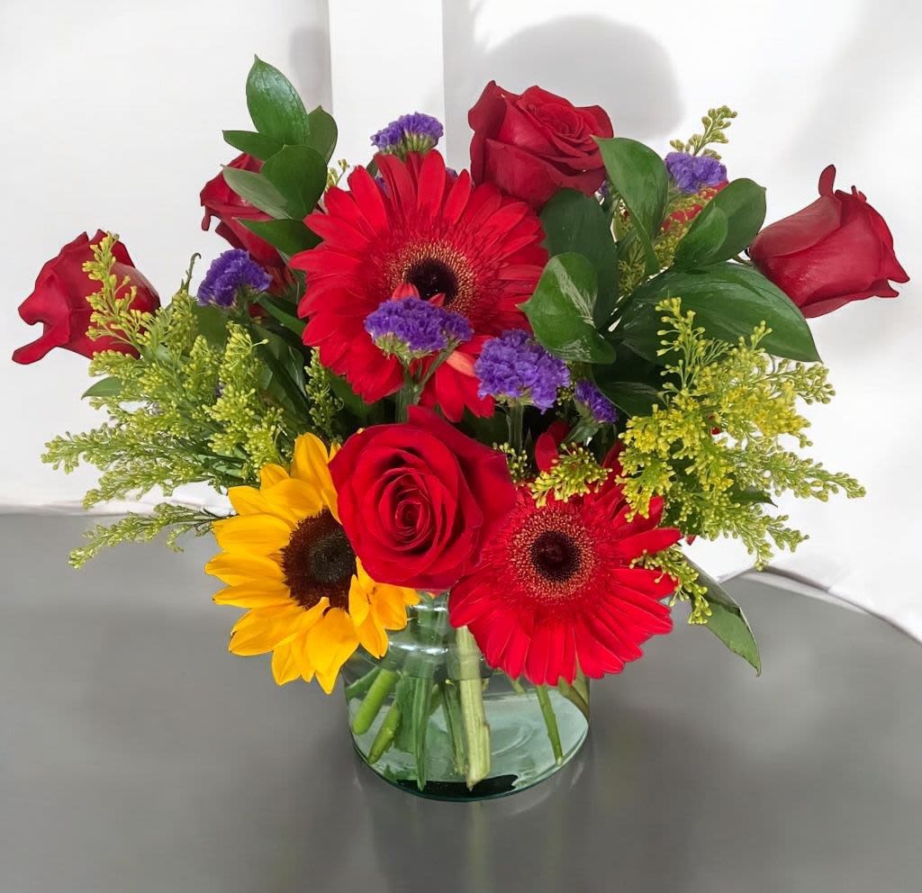 Jackie Bouquet - Jackie Bouquet with 100% real and fresh flowers in a vibrant mix of red gerbera, sunflower, and red roses. All Occasion Place your Order Online Monday to Saturday before 1:00 p.m. (E.T.) for same-day delivery. “Orders received after hours will be delivered the next business day”. Check our coverage area.  Occasionally, flowers or containers substitutions happen due to weather, seasonality, and market conditions, which may affect availability. If this is the case with the gift you’ve selected, we will ensure that your arrangement's style, theme, and color scheme are preserved and will only substitute items of equal value or higher value.  CARE INSTRUCTIONS  Keep the flower arrangement hydrated with natural water and change the water every two days. Do not spray any cleaning product on the flower arrangement. Do not place heavy objects directly on the flower arrangement. Keep flower arrangements out of direct sunlight and extreme heat.