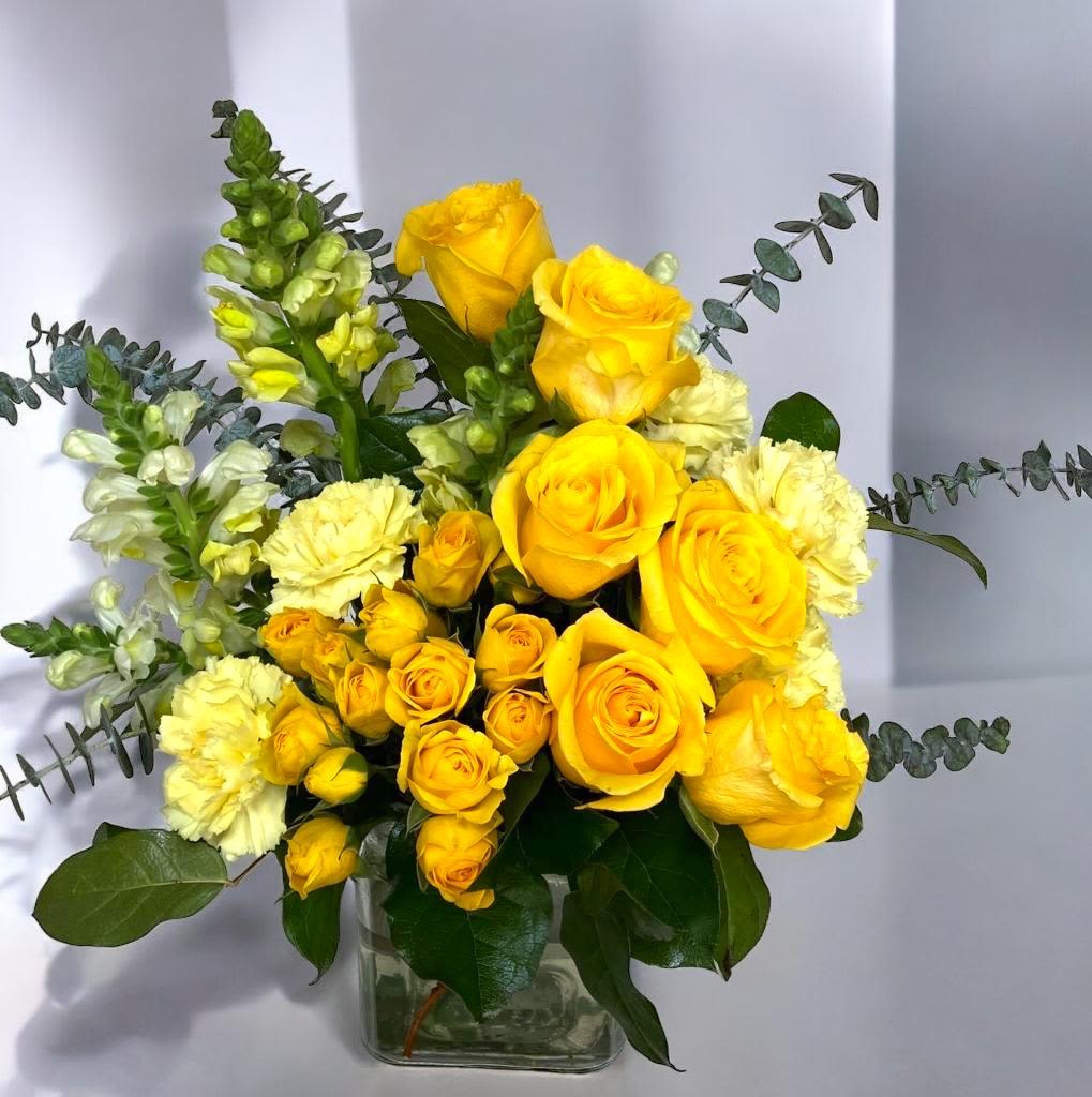 Yellow Harmony - Fresh flower arrangement along fine foliage. Glass Pot. Place your Order Online Monday to Saturday before 1:00 p.m. (E.T.) for same-day delivery.  “Orders received after hours will be delivered the next business day”. Check our coverage area. Occasionally, substitutions of flowers and/or containers happen due to weather, seasonality, and market conditions which may affect availability. If this is the case with the gift you’ve selected, we will ensure that the style, theme, and color scheme of your arrangement are preserved and will only substitute items of equal value or higher value.   CARE INSTRUCTIONS	 Keep the flower arrangement hydrated with natural water and change the water every two days. Do not spray any cleaning product on the flower arrangement. Do not place heavy objects directly on the flower arrangement. Keep flower arrangements out of direct sunlight and extreme heat. 