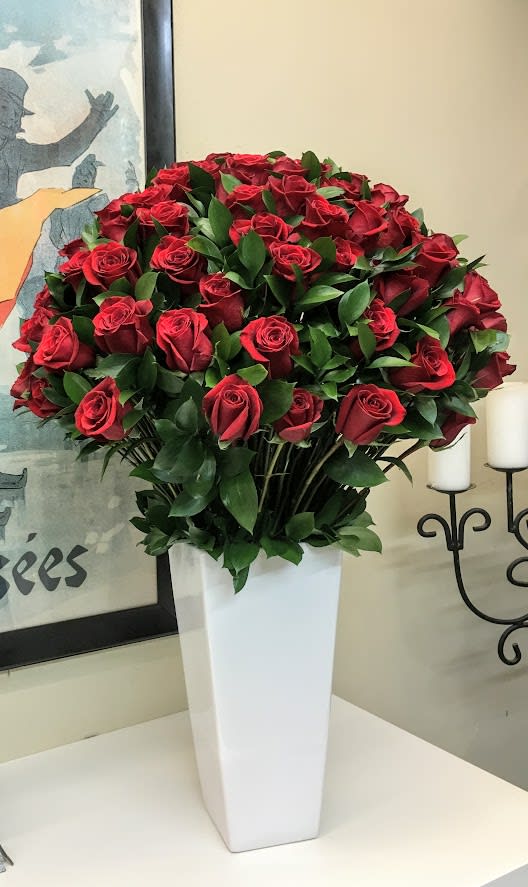 Dozens of Love - Elevate your Valentine’s Day celebration with &quot;Dozens of Love&quot;, a grand and luxurious floral arrangement that embodies passion, sophistication, and timeless romance. Designed for those who wish to make a bold statement of love, this exquisite centerpiece overflows with 48 velvety red roses creating a breathtaking display of beauty and desire.  Arranged in a sleek, modern white ceramic vase, this captivating floral creation is enhanced with delicate eucalyptus, and seasonal greenery, adding texture and depth to the composition.   Whether you are celebrating a romantic milestone, planning an unforgettable Valentine’s surprise, or expressing your deepest emotions, &quot;Dozens of Love&quot; is the ultimate luxury floral arrangement, guaranteed to leave a lasting impression.   Ideal for: Valentine's Day, Romantic Gestures, Anniversaries, Luxury Floral Centerpieces  Dimensions: Approx. 22&quot; high x 30&quot; wide #Luxury Valentine's Flowers,  #Grand RedRose Arrangement,  #Romantic Valentine's Gift,  #Premium Roses 