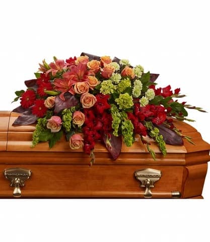 A FOND FAREWELL CASKET SPRAY - An overflowing of love and respect is joyfully expressed in this truly magnificent casket spray of orange roses and lilies and other brilliant blooms.  Approximately 44 W x 25 H