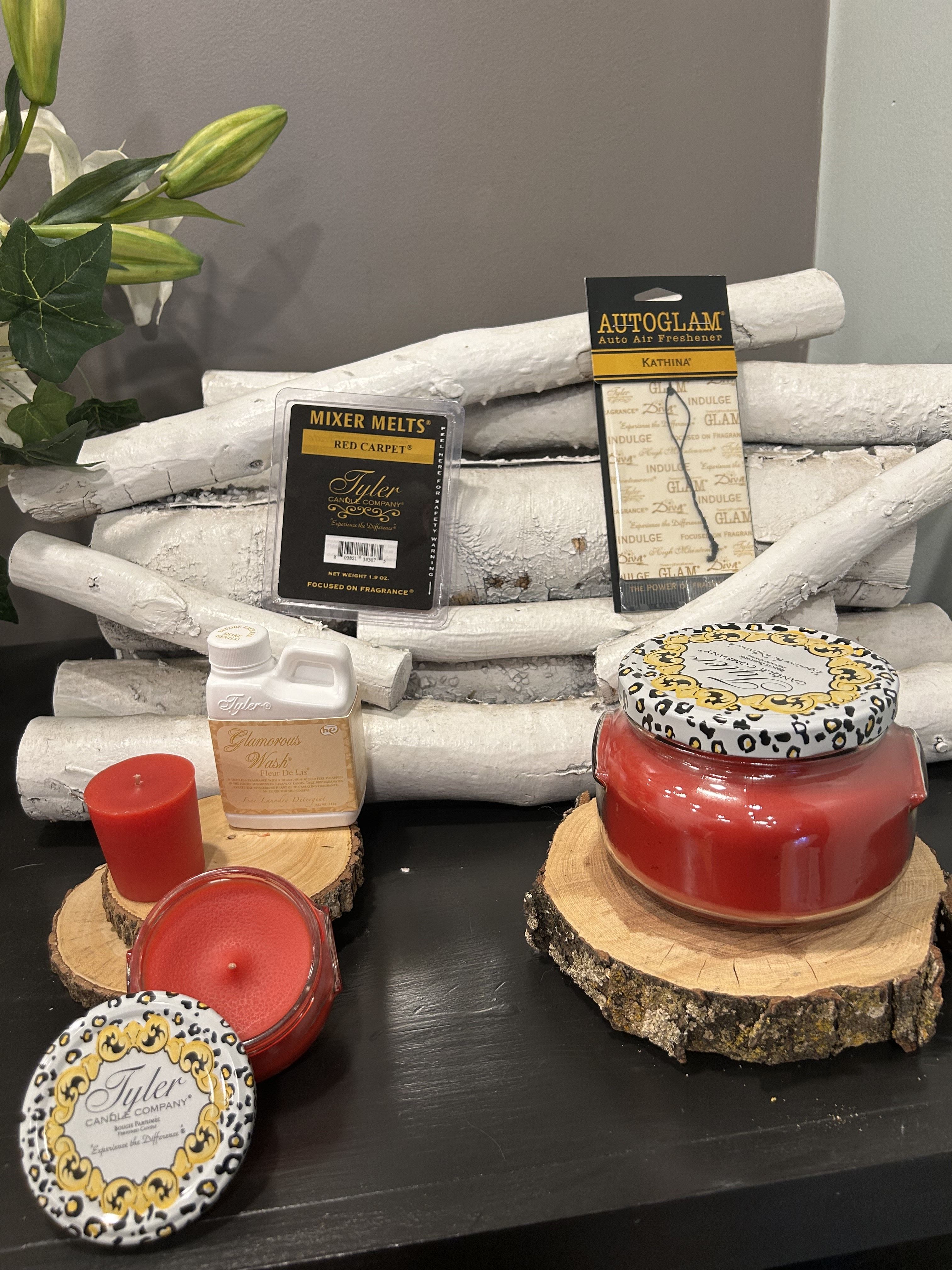 Red Carpet Candle Gift Set  - Red Carpet is like a true VIP experience in a bottle! The way you've described it, it's a bold and glamorous blend of Sicilian lemon and red passionfruit for a fresh, tropical opening, followed by a luscious heart of velvet plum, raspberry puree, and golden honey. The base of rich amber and exotic spices adds warmth and depth, making it a sophisticated, head-turning scent that's absolutely perfect for any glam lover.  The set includes:  Large 22 oz Candle – A statement piece that will fill your space with the opulent blend of tropical fruits, honey, and spices, setting a glamorous mood. Small 3.4 oz Candle – Perfect for creating that luxurious ambiance in smaller rooms or even for travel, so you can enjoy this sophisticated scent anywhere. 15 hr Votive (112g) – Ideal for a more concentrated experience of the fragrance, making it perfect for a smaller space or a shorter period of indulgence. Luxury Laundry Detergent – Infuse your clothes with that radiant, fruity-spicy scent, leaving them feeling as glamorous as the fragrance itself. Autoglam Car Air Freshener – Turn your car into a VIP space with this rich, exotic blend, giving every drive a touch of elegance. Wax Melts – Enjoy the luxurious scent throughout your home without needing an open flame, making your space feel as exclusive as a red carpet event. This fragrance set really screams &quot;glam squad&quot; — perfect for someone who loves to feel like a star and enjoy a sophisticated, yet tropical scent.