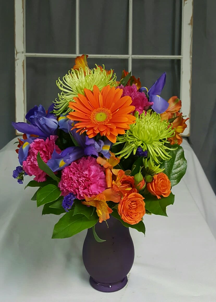 Razzle Dazzle Razzle Dazzle - This Bright and Vivid Arrangement includes Purple Iris and Statice, Green Spider Mums, Hot Pink Carnations, Orange Gerbera Daisies, Spray Roses and Alstromeria
