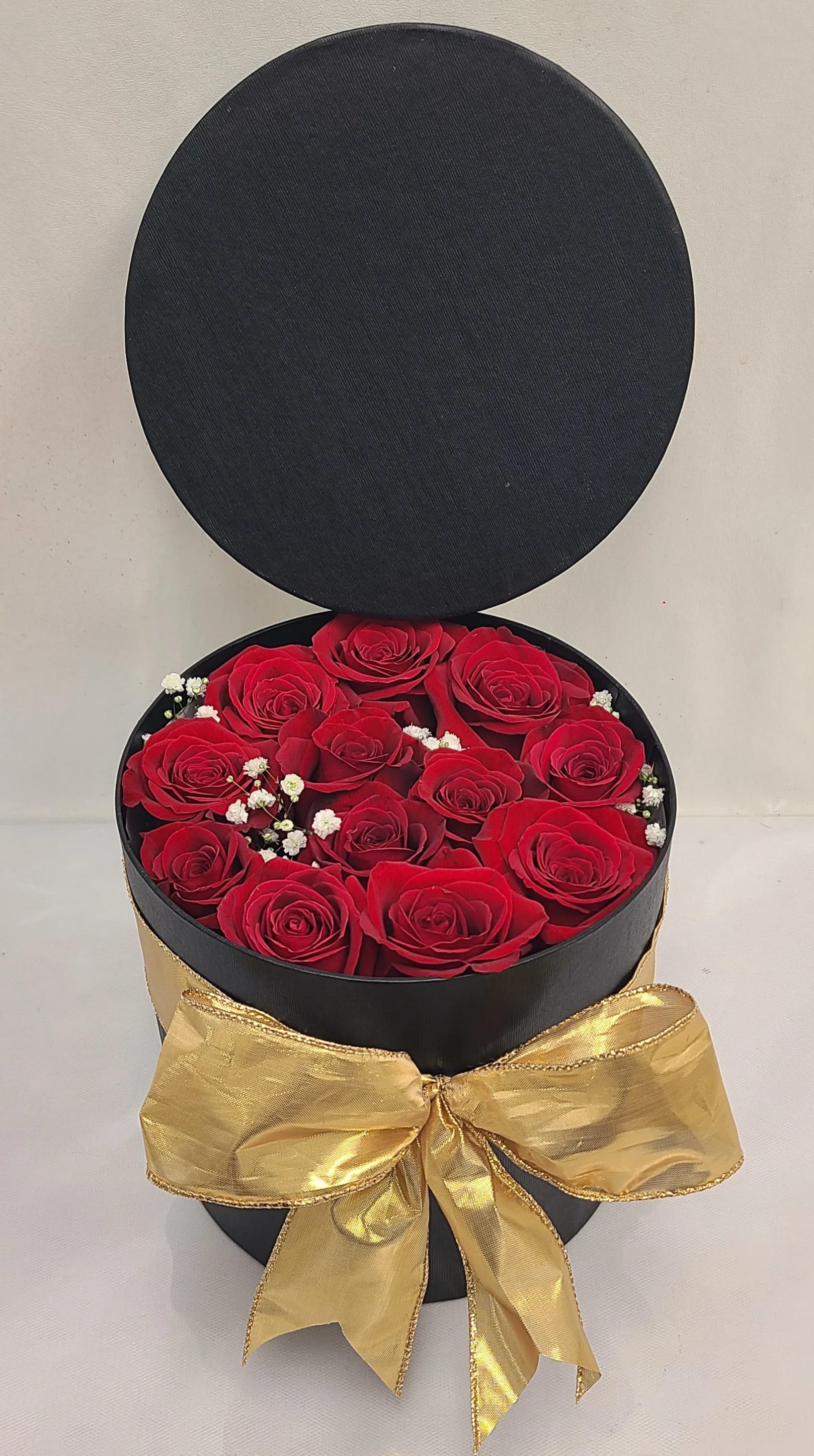 Red Secret Box - Very Elegant Black round box with a lid field with 12-14 red roses and Baby breath.