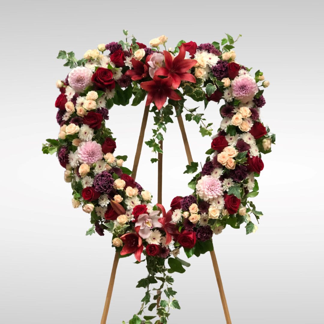Deep Love Heart Wreath (displaying premium) Deep Love Heart Wreath (displaying premium) - Recipe: Mix of pink, blush, purple and red flowers on a heart shaped wreath. Seasonal: Seasonal Dahlias Orientation: Front Facing View Photo shown: Premium