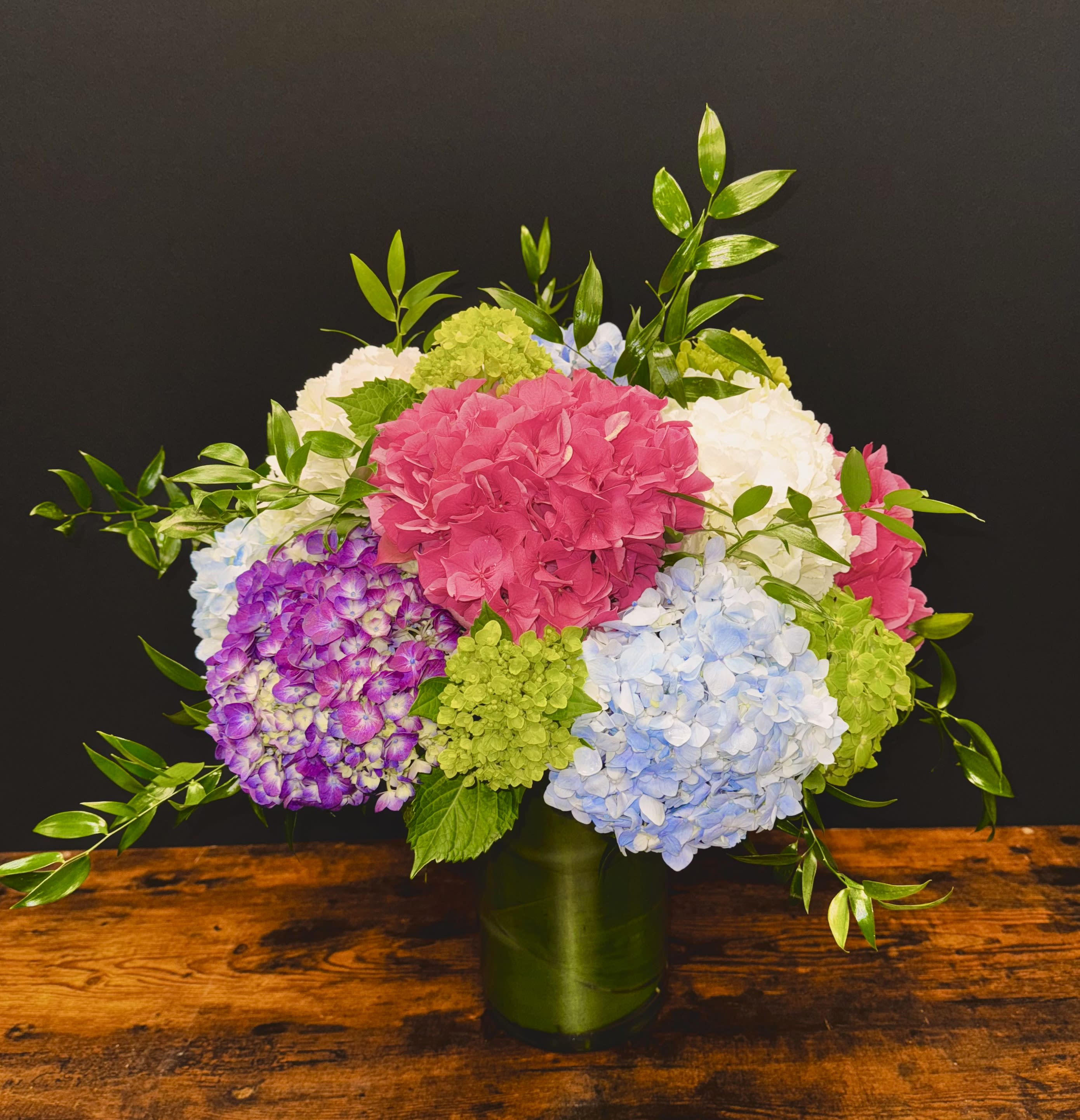 Happy Hydrangeas- tall and showy Happy Hydrangeas- tall and showy - This arrangement is a mix of all Dutch and South American hydrangeas. The colors will be as similar as possible based on freshness and availability. Please call the shop if you would like to request a certain color scheme. Colors will vary with each season.