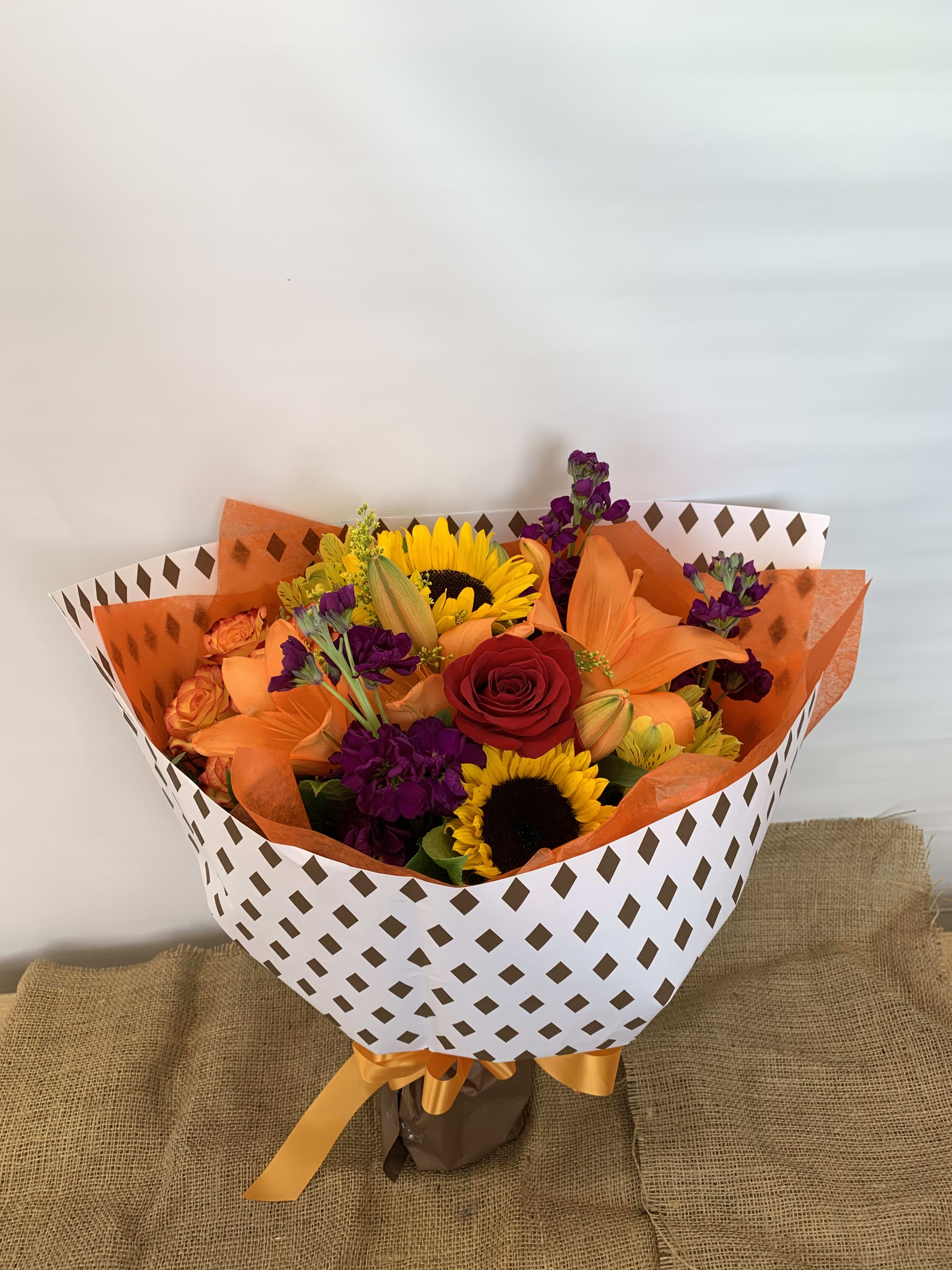 Autumn Colors Wrapped Bouquet  - Designer Choice—Our florist designer will use seasonal flowers for a unique bouquet. Prices and availability of seasonal flowers may vary. We are always eager to discuss any product requests. Let us know if you have any color or flower preferences and we will do our best to accommodate your needs.