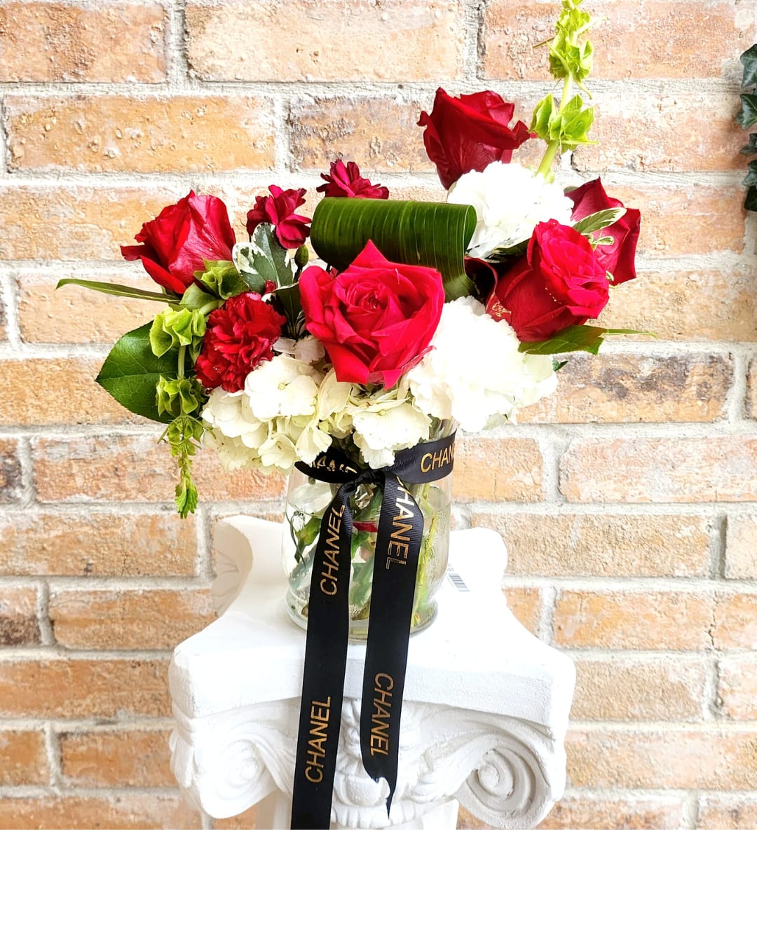 Birds Of Feathers Birds Of Feathers - A vibrant blend of red and white blooms, elegantly complemented by a touch of a Chanel Ribbon in clear vase