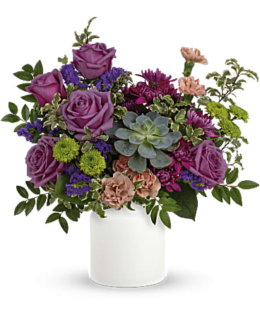 Hidden Garden   - Lavender roses, soft peach carnations, purple sinuata statice all pair organically with an echeveria succulent. Delivered in a matte white Savannah Jar.