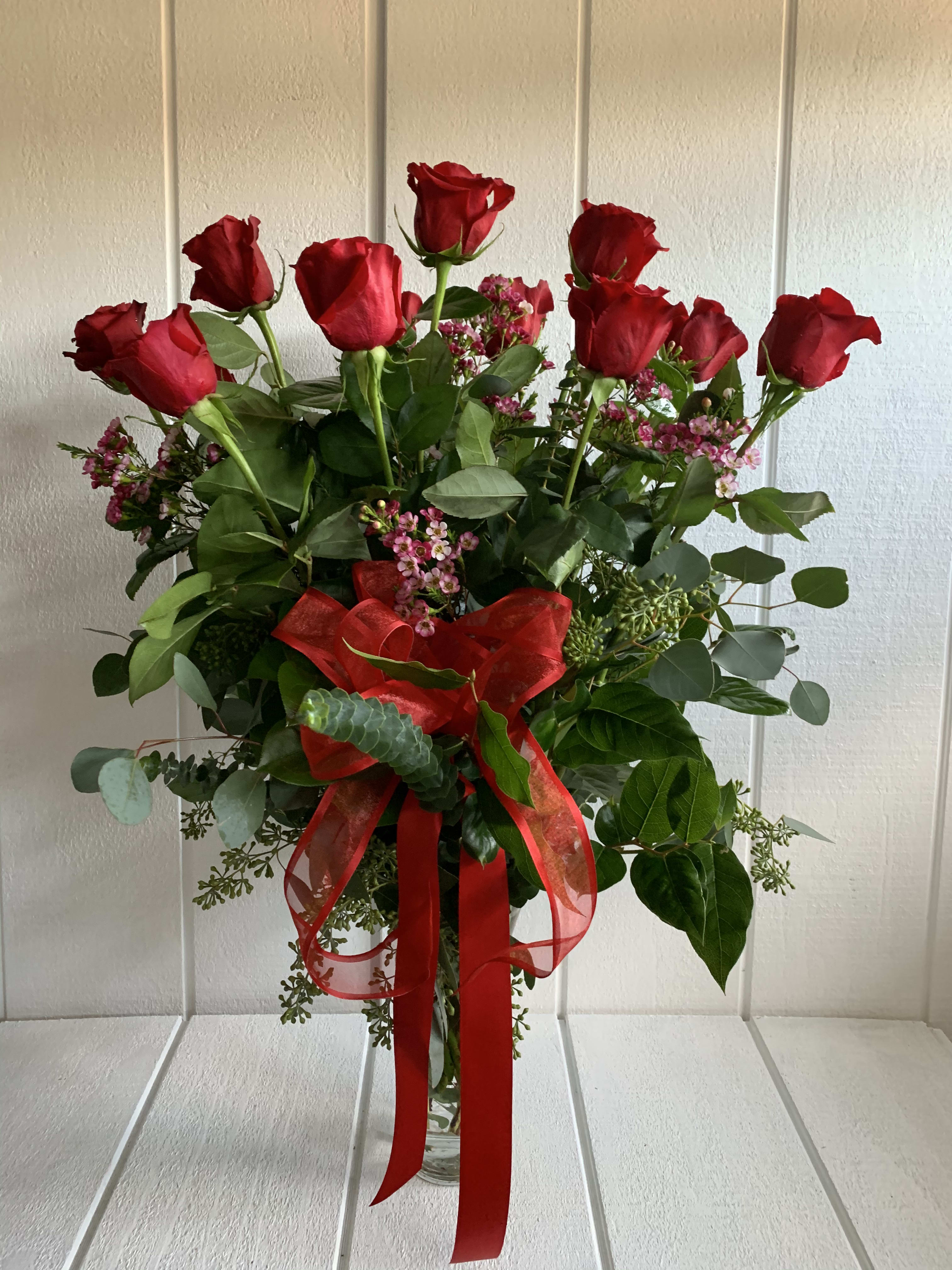 Dozen Long Stem Red Roses - A dozen long stems red roses with red ribbon and greenery in a clear vase.