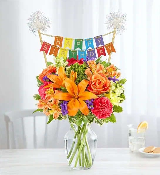 Vibrant Floral Medley with Happy Birthday Banner - All-around arrangement with orange roses, Asiatic lilies and Peruvian lilies (alstroemeria); hot pink carnations; yellow snapdragons and purple statice; accented with green trachelium and assorted greenery WITH HAPPY BIRTHDAY BANNER