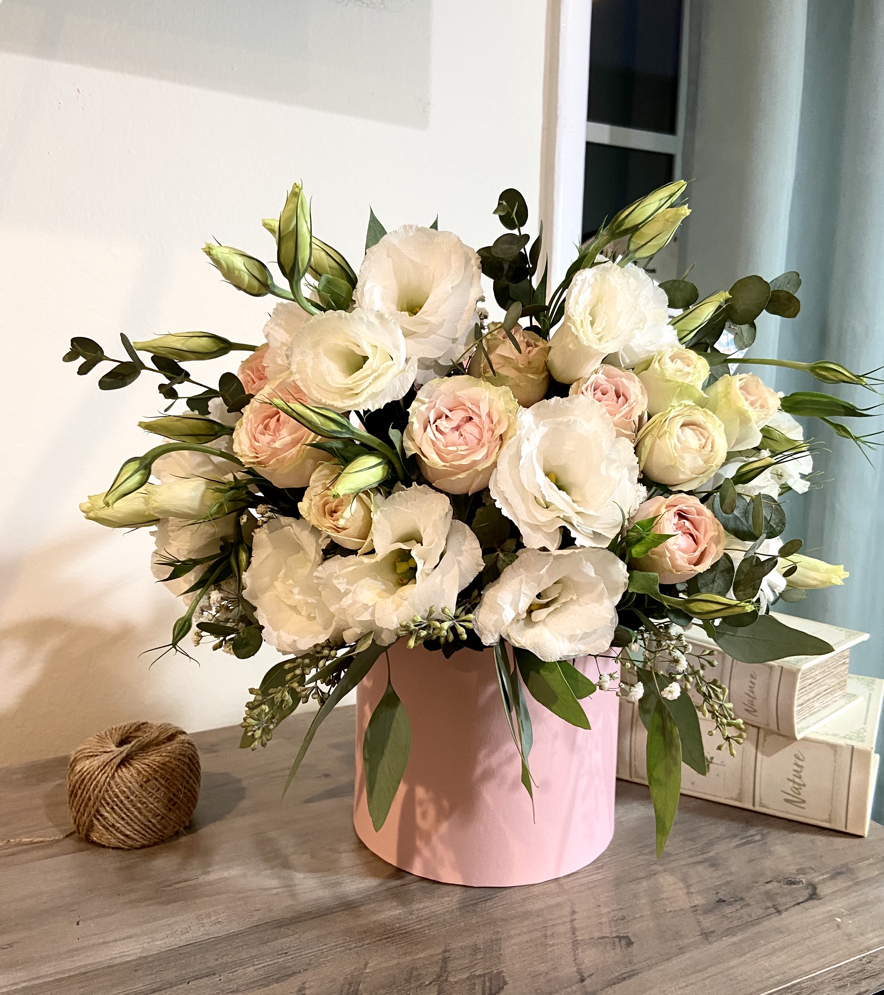 66S- Pink box with Lisianthus - This elegant arrangement in a pink box features a delicate combination of white lisianthus and soft pink roses. The gentle contrast between the pure white blooms and blush-toned roses creates a fresh and romantic look, making it an ideal gift or centerpiece for special occasions, exuding timeless beauty and grace. STANDARD size is shown in the picture.