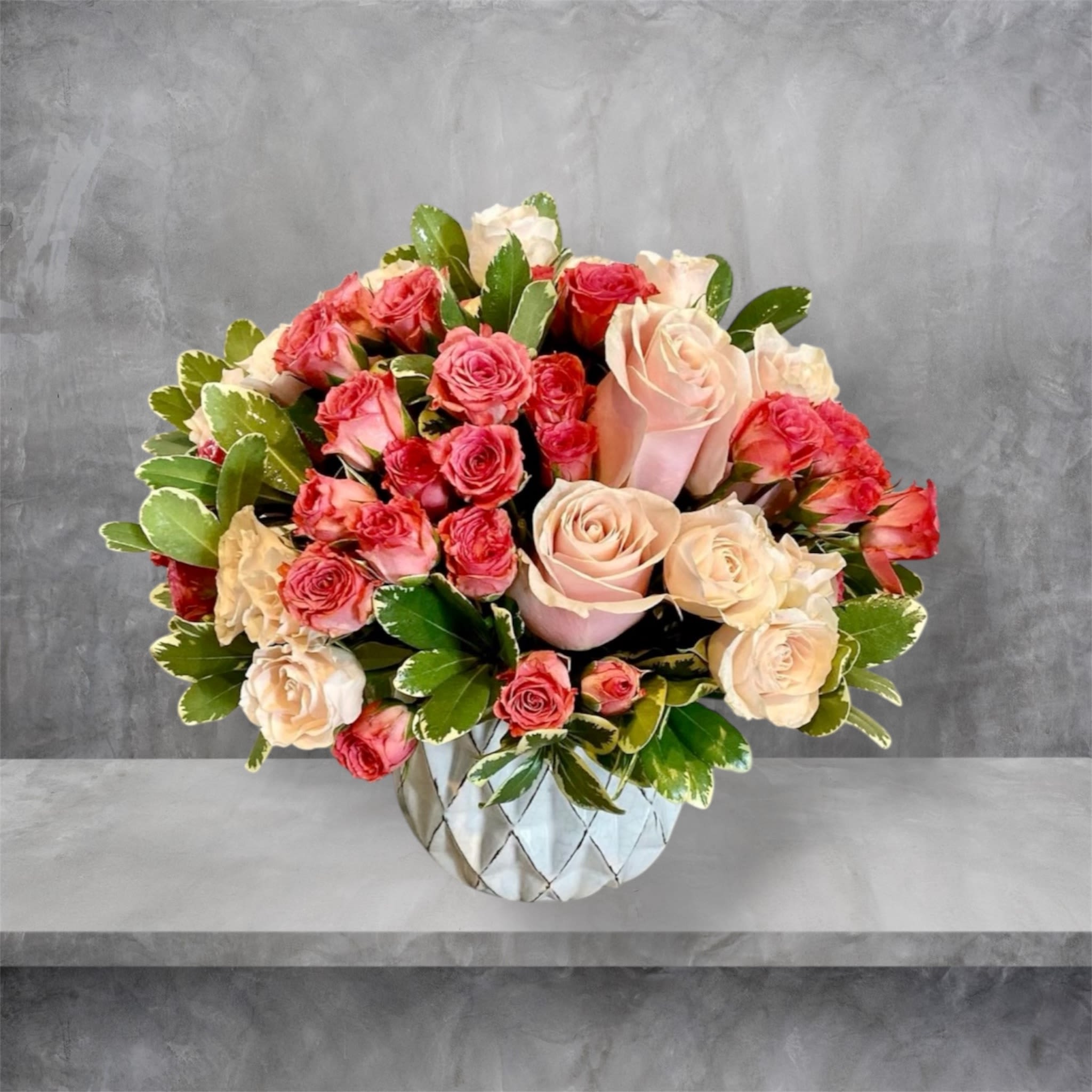 Blush - A beautiful mix of pink and blush roses with foliage in a ceramic vase.