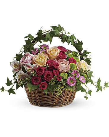 KF_T147-3A Fairest of all KF_T147-3A Fairest of all - A fairy tale…in flowers! Delicate ivy climbs the handle of this round wicker basket that's home to a feminine garden of fuchsia flowers. You can almost imagine garden sprites dancing through the country style arrangement! A round wicker basket holds an array of fresh flowers including hot pink roses, pale orange roses, pink ranunculus, pink alstroemeria, light pink matsumoto asters and green button mums. Ivy, seeded eucalyptus and oregonia add lush greenery. Orientation: All-Around