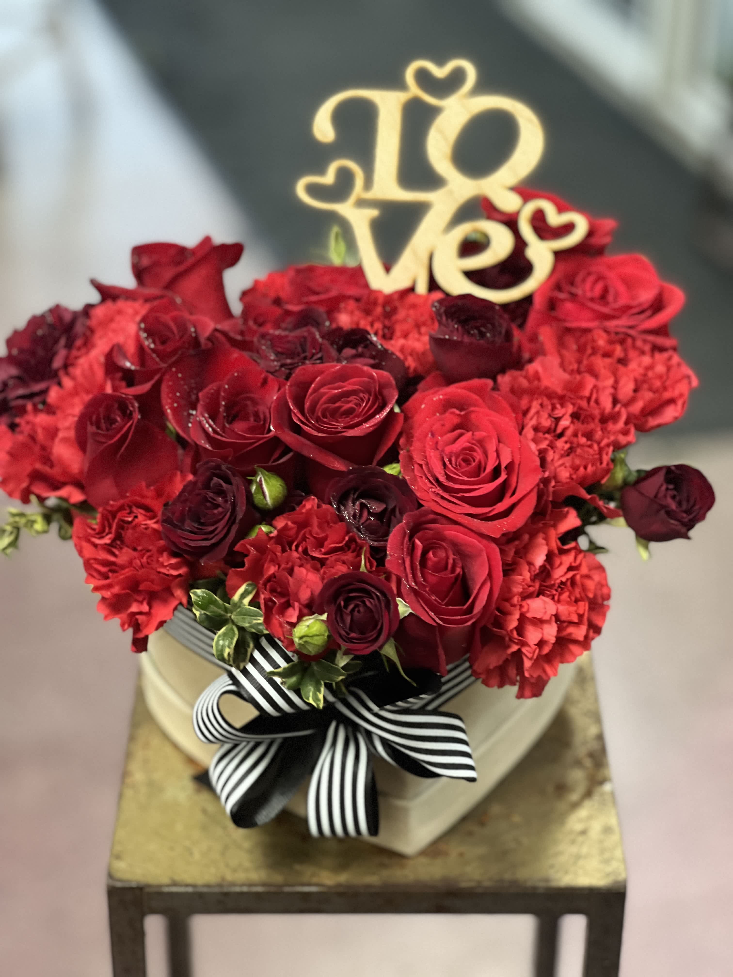 I love you so much - Simply adorable, red flowers, arranged in headbox decorated with romantic ribbon tied around the box and LOVE wooden pick added 