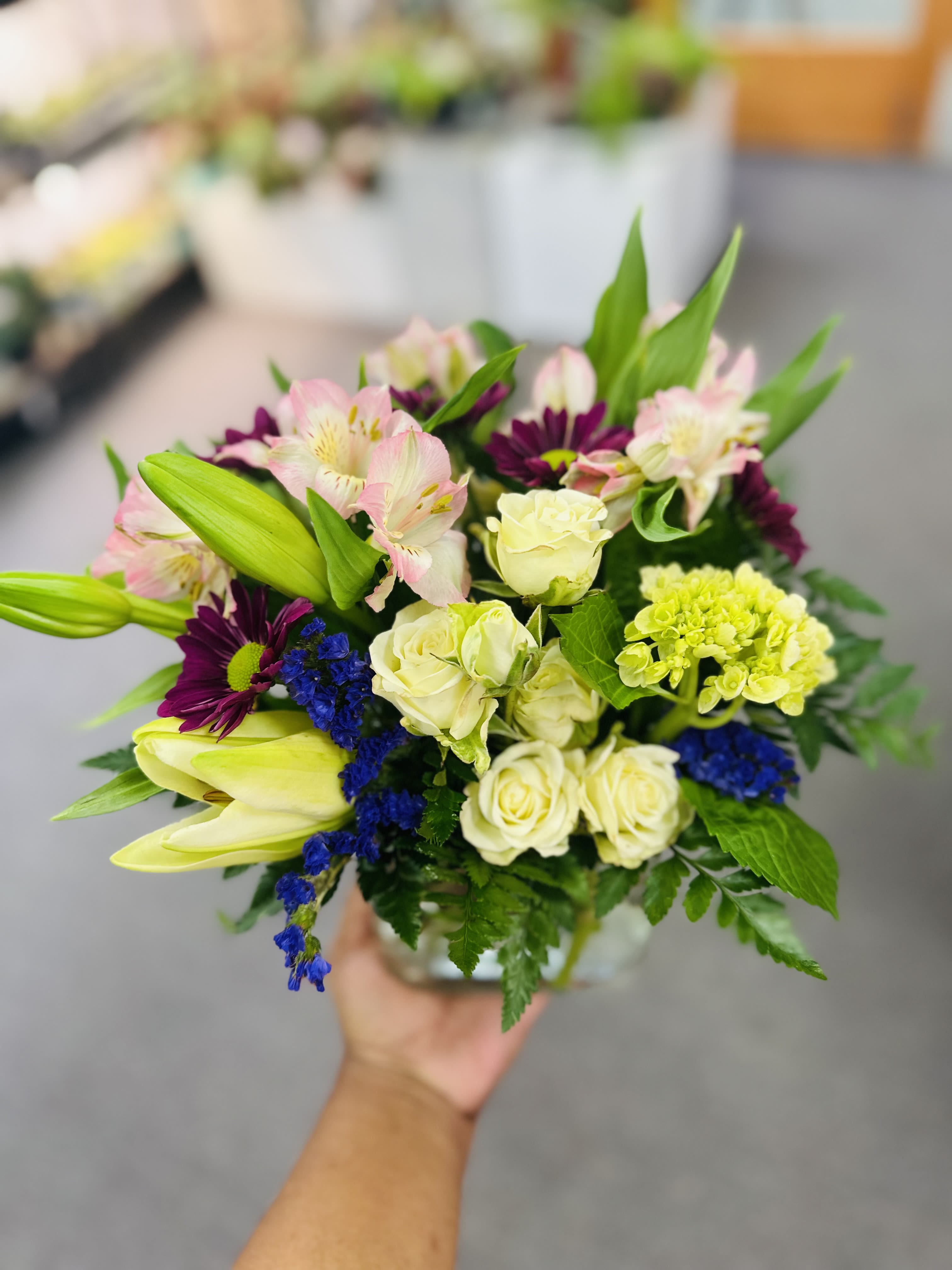 White in Lovely  - Hello, gorgeous! This lovely bouquet includes white/green hydrangea, white spray roses, and white Asiatic lilies arranged in our vibrant white glass cube.  Green/white hydrangea, lspray roses, white Asiatic lilies, dark pink alstroemeria, and statice are accented with assorted greens. 