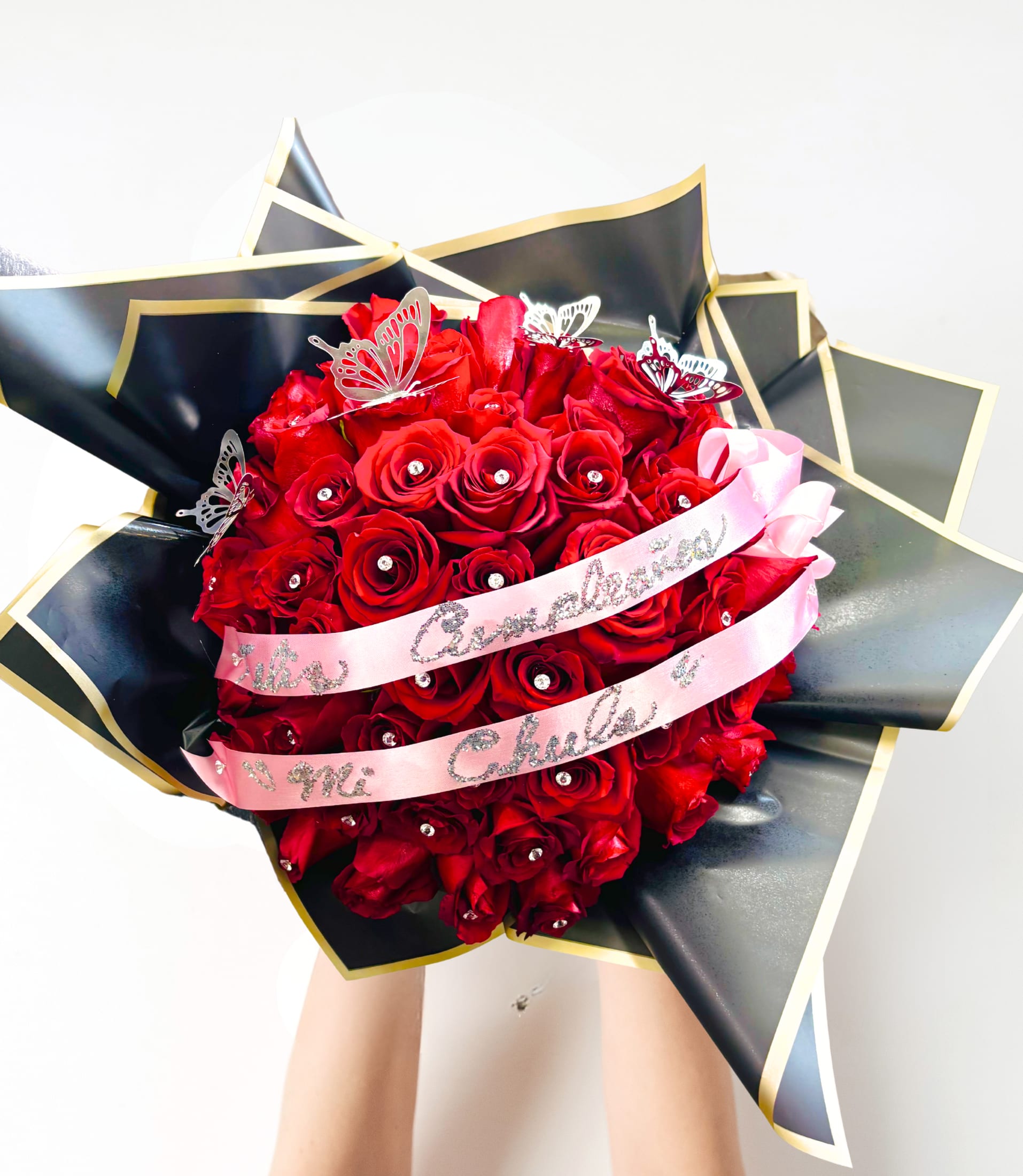 Butterfly Magic Butterfly Magic - This stunning bouquet is designed with 50 beautiful Ruby Red Roses and stud accents, With Silver or Gold Butterflies, And Personalized Sash. Wrapped in elegant paper and ribbon tied. (Hand-tied Bouquet, No vase included) The Perfect Bouquet for an Everlasting impression!