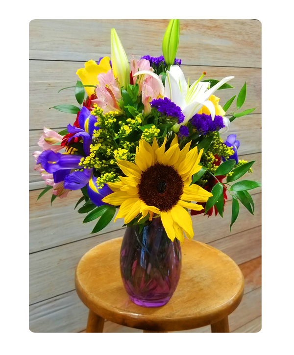  Ray of Sunshine - Brighten their day with this vibrant arrangement of bright sunflowers and blue iris and yellow lilies.