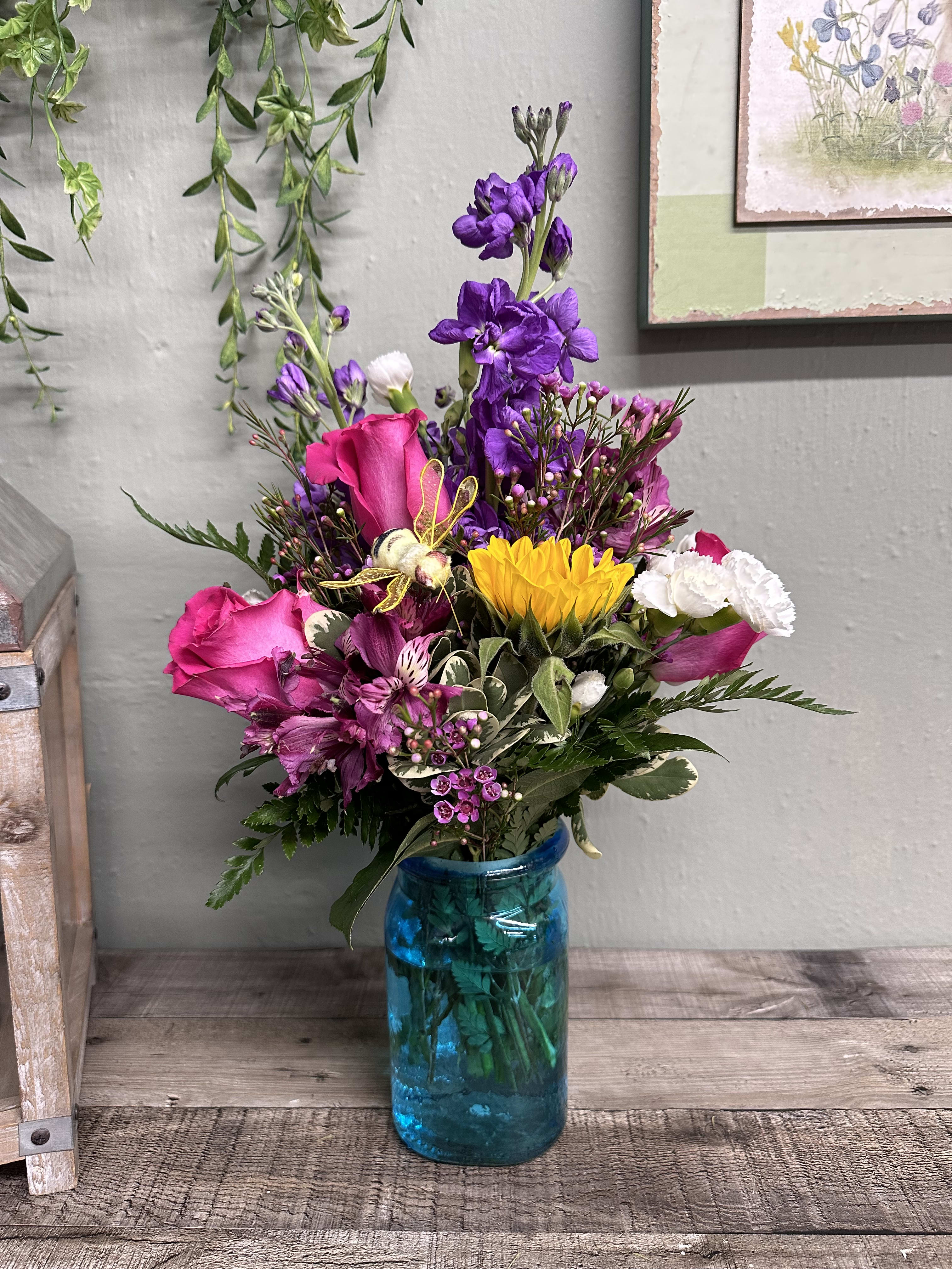 Colors of Spring Colors of Spring - A 6 1/2 inch glass hammered jar vase, one of four colors. The arrangement will be all the way around with flower colors to compliment the vase. Seasonal flowers, the freshest available might be daisies, carnations, pixie carns, alstroemeria, filler flowers and taller line flowers. We will make it awesome, and springy fresh.
