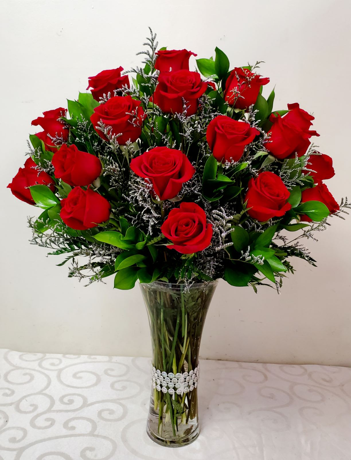 Love Of My Life Bouquet - 25 Long Stems Roses in a Tall Accented Vase  These beautiful red roses accented with exotic greens and sprays of Misty Blue are sure to impress. The  Perfect gift for someone you love.  Approximately  23&quot; High by 17&quot; Wide 