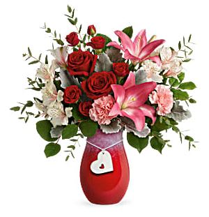 Charmed In Love Charmed In Love - Take her Valentine's Day breath away with this passionate red rose and white lily bouquet, presented in an artisanal stoneware vase with chic ombre look and sweet ceramic heart charm.