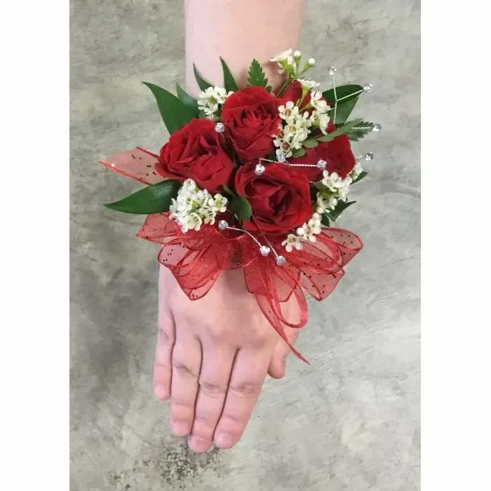 Red Rose Corsage Red Rose Corsage - red roses with white accent and silver rhinestones. Corsage is adorned on a standard elastic wrist-let. If you wish any substitutions You Must Contact our store directly. To guarantee the corsage as shown above we need 48 hours notice. Colors of flowers can vary slightly to the one shown on our website