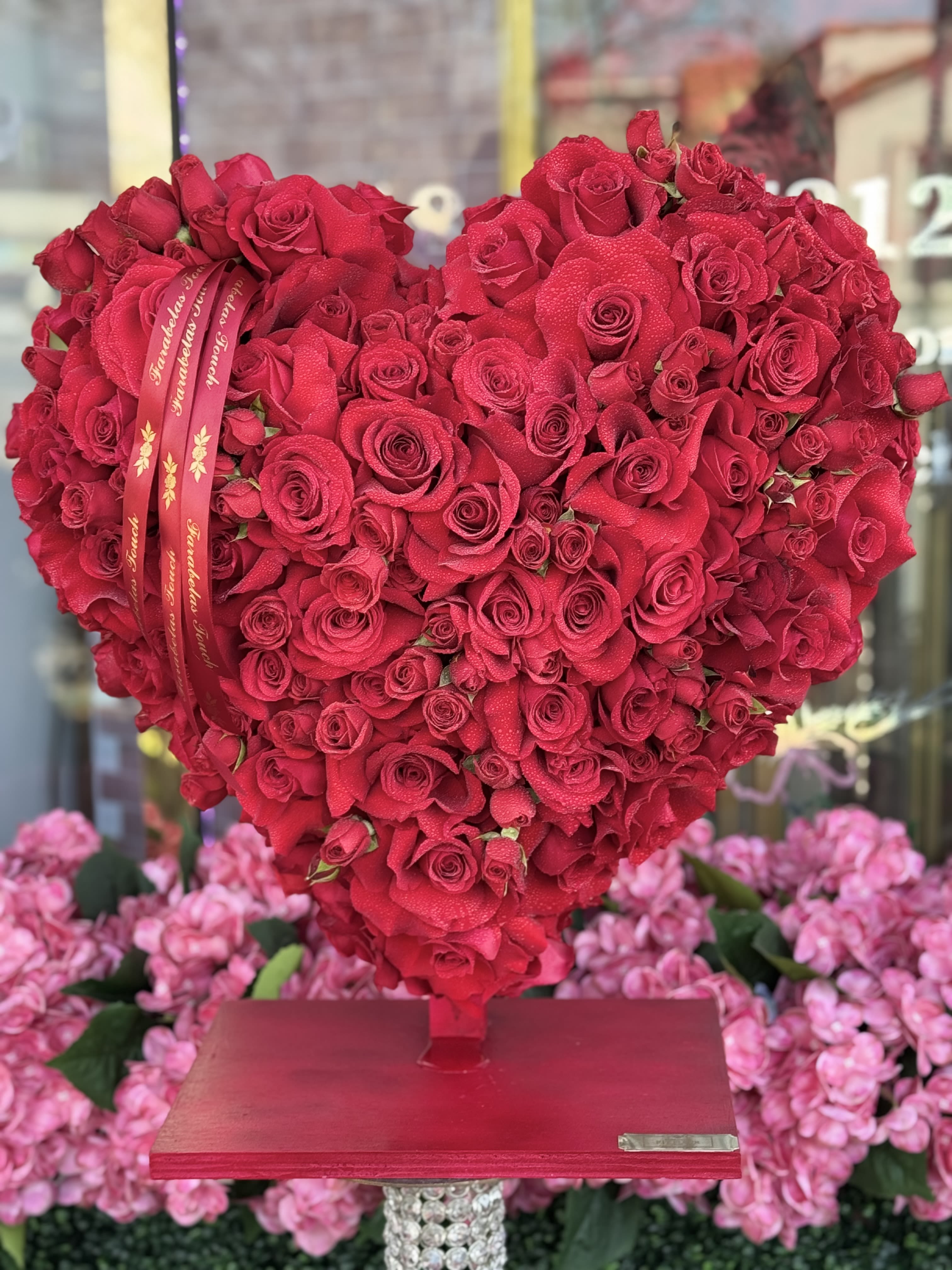 Cupids heart  - **Product Bio: Heartfelt Elegance - Red Rose Heart Arrangement**  Celebrate your special moments with our exquisite Heart-Shaped Arrangement, crafted entirely from lush red roses and delicate spray roses. Designed by our talented team of handpicked floral designers, this stunning display is the perfect way to express your love and appreciation for any occasion.   Whether it's an anniversary, birthday, or just because, this arrangement embodies elegance and passion, making it a beautiful centerpiece that will leave a lasting impression. Each bloom is thoughtfully selected to ensure freshness and vibrancy, creating a romantic atmosphere that resonates with heartfelt emotions.   Let this enchanting floral masterpiece be a part of your cherished celebrations, bringing warmth and joy to your loved ones. Experience the art of floral design with our Heartfelt Elegance arrangement, where every petal tells a story of love.