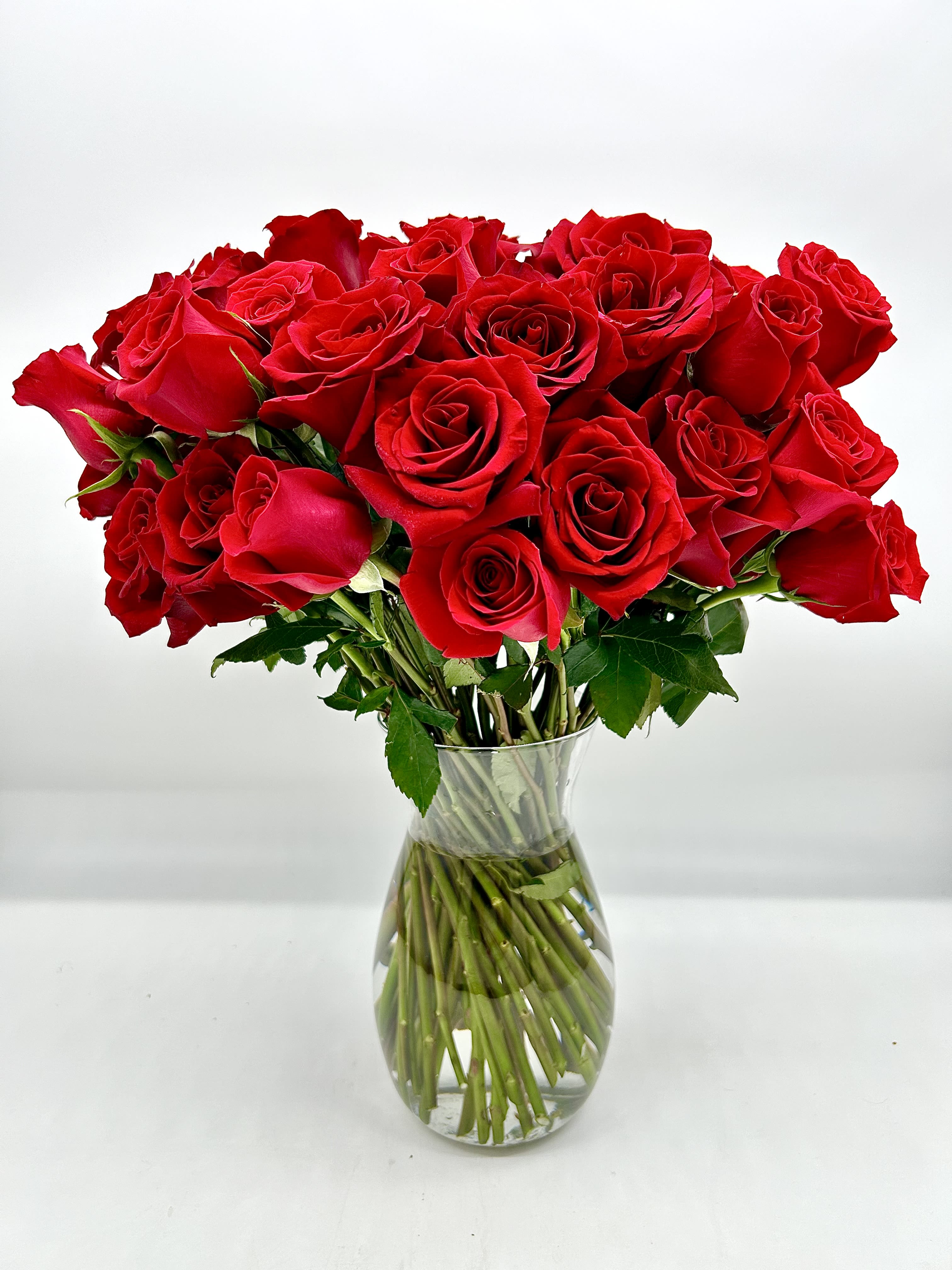 Crimson Devotion  - Crimson Devotion is an extraordinary floral arrangement featuring 50 lush red roses, each one a symbol of deep love, passion, and unwavering commitment. The arrangement is designed to make a bold, heartfelt statement, capturing the intensity of affection in its vibrant blooms. Perfect for marking a significant milestone such as an anniversary, a special occasion, or expressing profound love and admiration, this lavish bouquet is sure to leave a lasting impression. Its elegance and beauty convey the depth of your emotions in a timeless and unforgettable way. All bouquets are arranged by our professional floral design team accented with seasonal filler (i.e. greenery, baby’s breath, etc.) inside an elegant glass vase or gift box.   Blooms are hand delivered in person to enhance any celebration or a “just because” surprise. Deliveries are done between 10am - 5pm. If the recipient is not home we will leave the delivery if safe from the elements. We will call or text the recipient and let them know a delivery has been left.