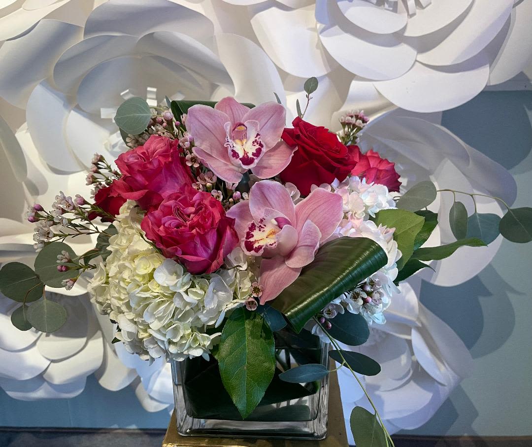 Orchid Elegance Orchid Elegance - This best seller is simply gorgeous!! Screaming love and elegance with three fresh cut pink cymbidium orchids; six pink and red roses; and hydrangeas in a large glass cube vase. Cheers!