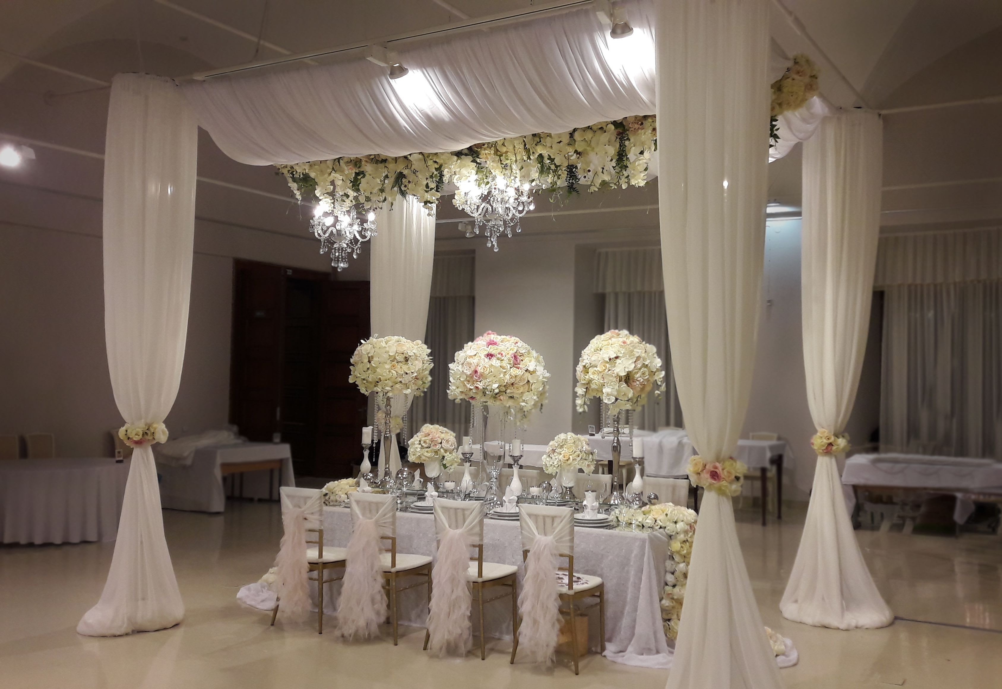 Wedding decor Los Angeles - Luxurious wedding decor in soft white and cream tones, creating an atmosphere of elegance and sophistication. The centerpiece features exquisite floral arrangements, complemented by delicate fabrics and crystal accents. Perfect for a dream wedding in Los Angeles, this decor enhances the refined style of your celebration. We specialize in custom designs for wedding receptions, arches, and photo zones, making your day unforgettable. Order wedding decorations from professionals and turn your event into a fairytale. Personalized approach, premium flowers, and attention to detail for your perfect day.