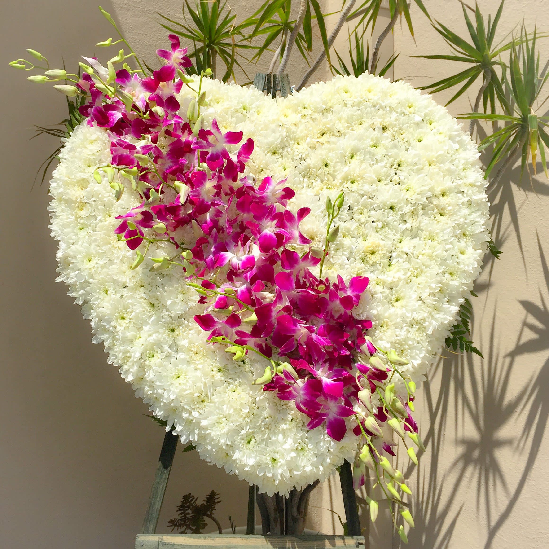 Orchids And Heart Standing Spray - An elegant bouquet of all purple dendrobium orchids artistically arranged in a solid heart standing spray bouquet filled with white chrysanthemums. Guaranteed to “WOW”! Easel included.  Approximately 24” D