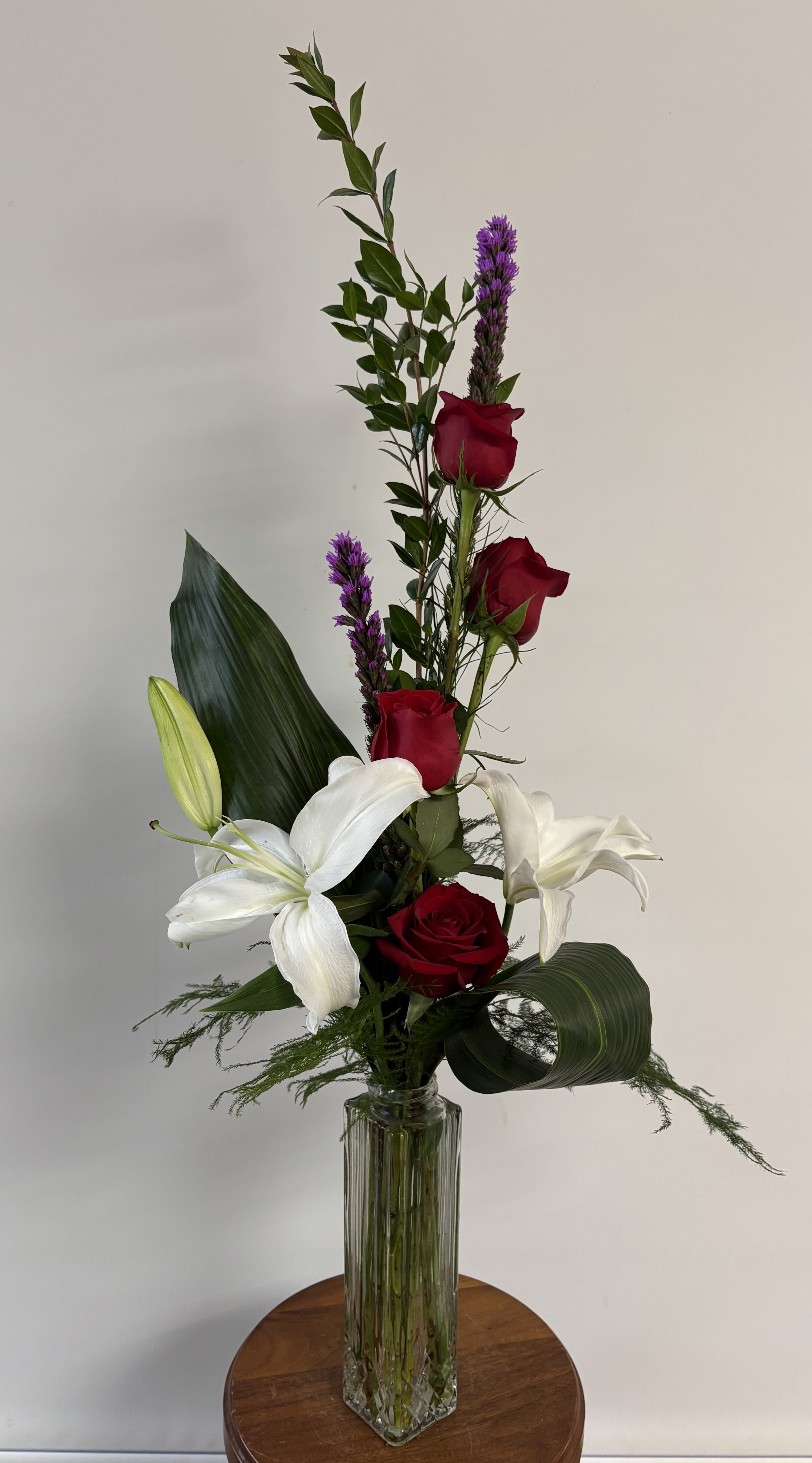 A Touch of Class - A high-styled arrangement of lilies, roses, and liatris with specialized greenery in a rectangular, clear vase.