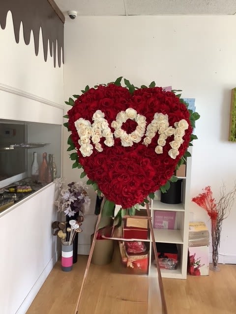 "MOM" Heart-Shaped Funeral Tribute "MOM" Heart-Shaped Funeral Tribute - Honor a beloved mother with this stunning heart-shaped floral tribute, designed to express love, gratitude, and remembrance. Featuring lush red roses as the base, with the word "MOM" beautifully crafted in elegant white roses, this arrangement symbolizes eternal love and appreciation.