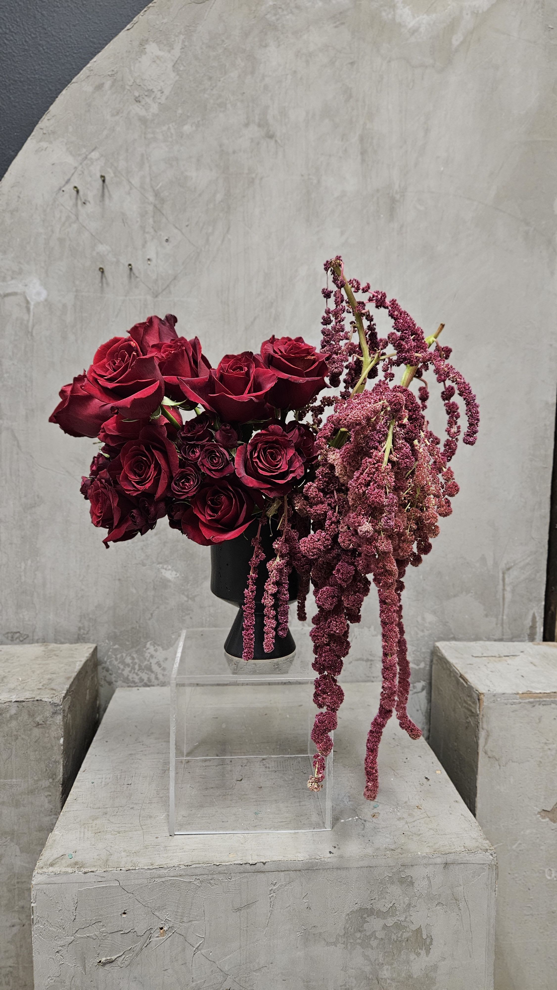 Love’s Embrace Love’s Embrace - Elevate any space with Love’s Embrace—a striking floral arrangement featuring deep red roses paired with cascading amaranthus for a dramatic, modern touch. Set in a sleek black vase, this design exudes passion, elegance, and artistic sophistication. A bold statement for any occasion.