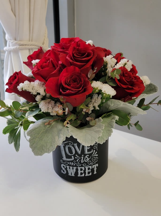 Sweet Love Sweet Love - With all of you're heart call out their name " Sweet Love" and give them this floral creation that says just that. Medium 50 cm red explorer roses arranged with dusty miller, eucalyptus and white statice in a black modern ceramic cylinder style vase. Standard, 8 roses, Deluxe,14 roses and Premium,18