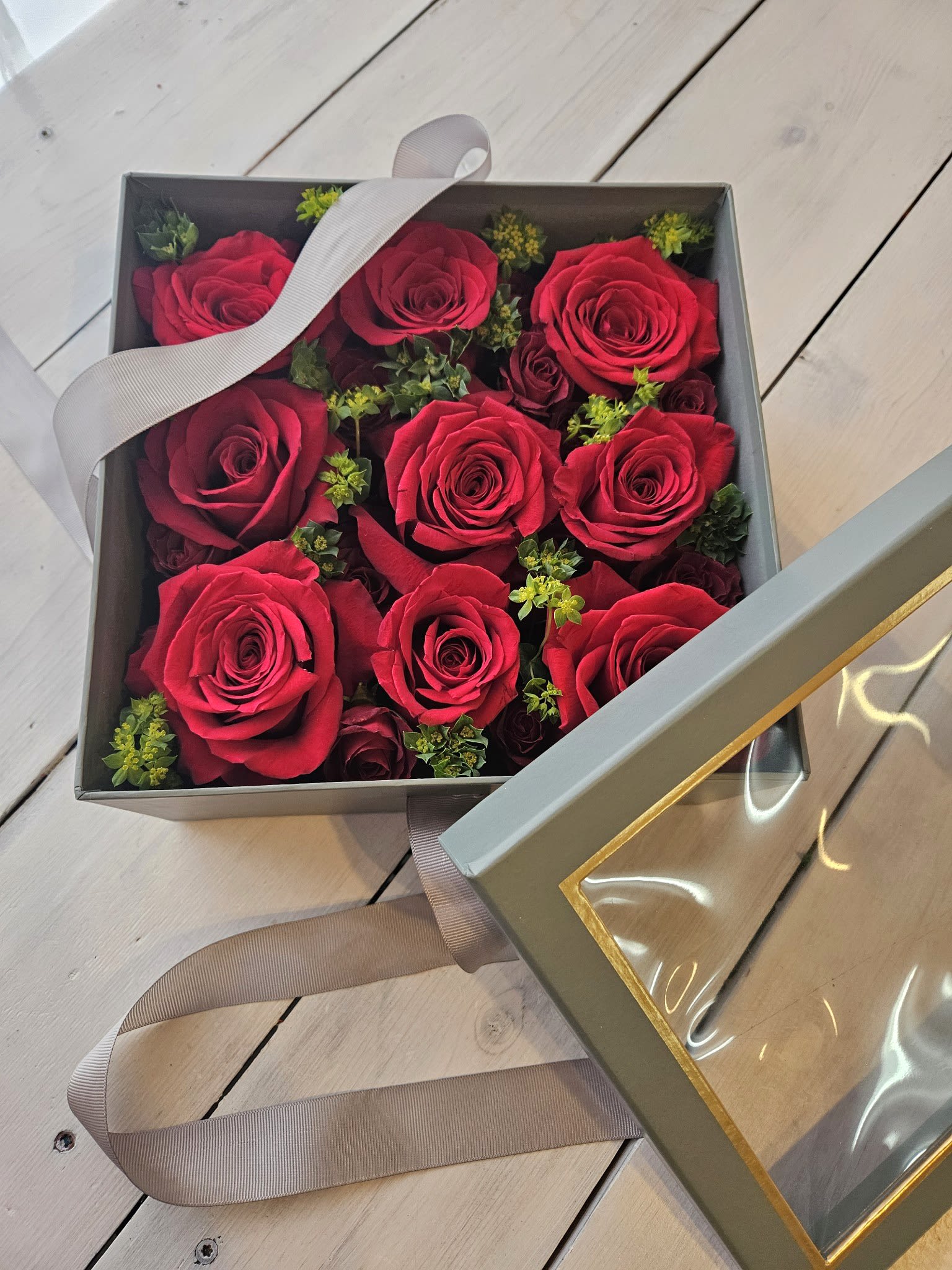 Charming Rose Box - Low lush roses nestled beautifully in a soft gray peak-a-boo box. Its a sleak design housing roses, spray roses and bupleurum giving dimension and texture to the design.