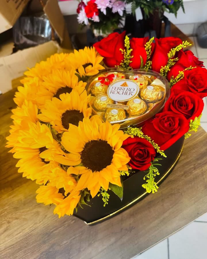 Sunny Surprise Sunny Surprise - Sunflowers and red roses arranged beautifully in a heart shaped box with a Ferraro heart shape surprise. Chocolates may vary because of seasonal availability.