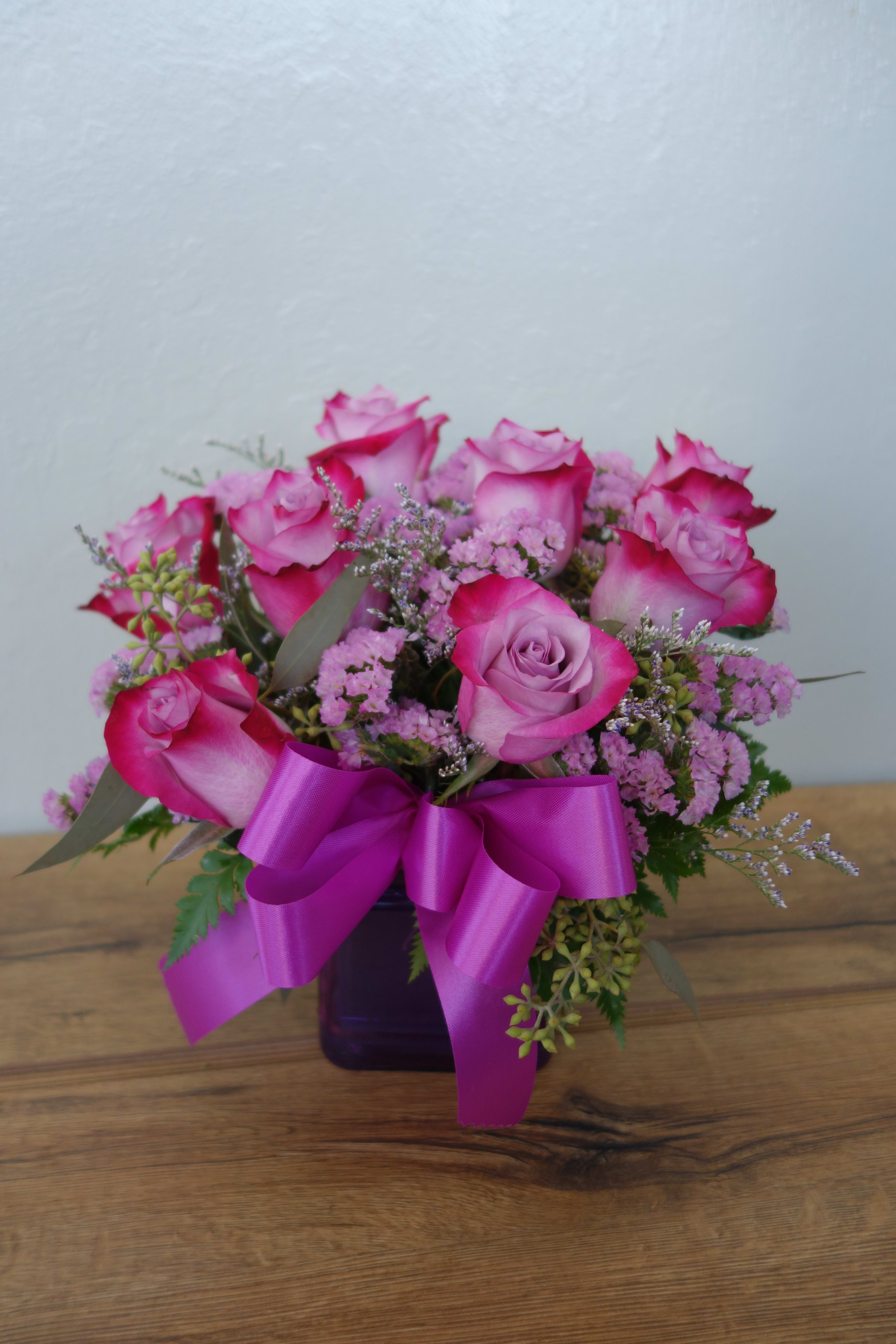 Morning Melody - Shades of purple are in perfect harmony in this profoundly pretty arrangement. A lovely mix of classic and modern, ribbons and roses, it's sure to make someone's day!  Lavender roses and waxflower, purple limonium and greens are hand-delivered in a lavender cube that's all wrapped up with a vibrant purple taffeta ribbon.  Approximately 10 1/2&quot; W x 11&quot; H  Orientation: All Around  As Shown : 8 stems Deluxe : 10 stems Premium : 12 stems